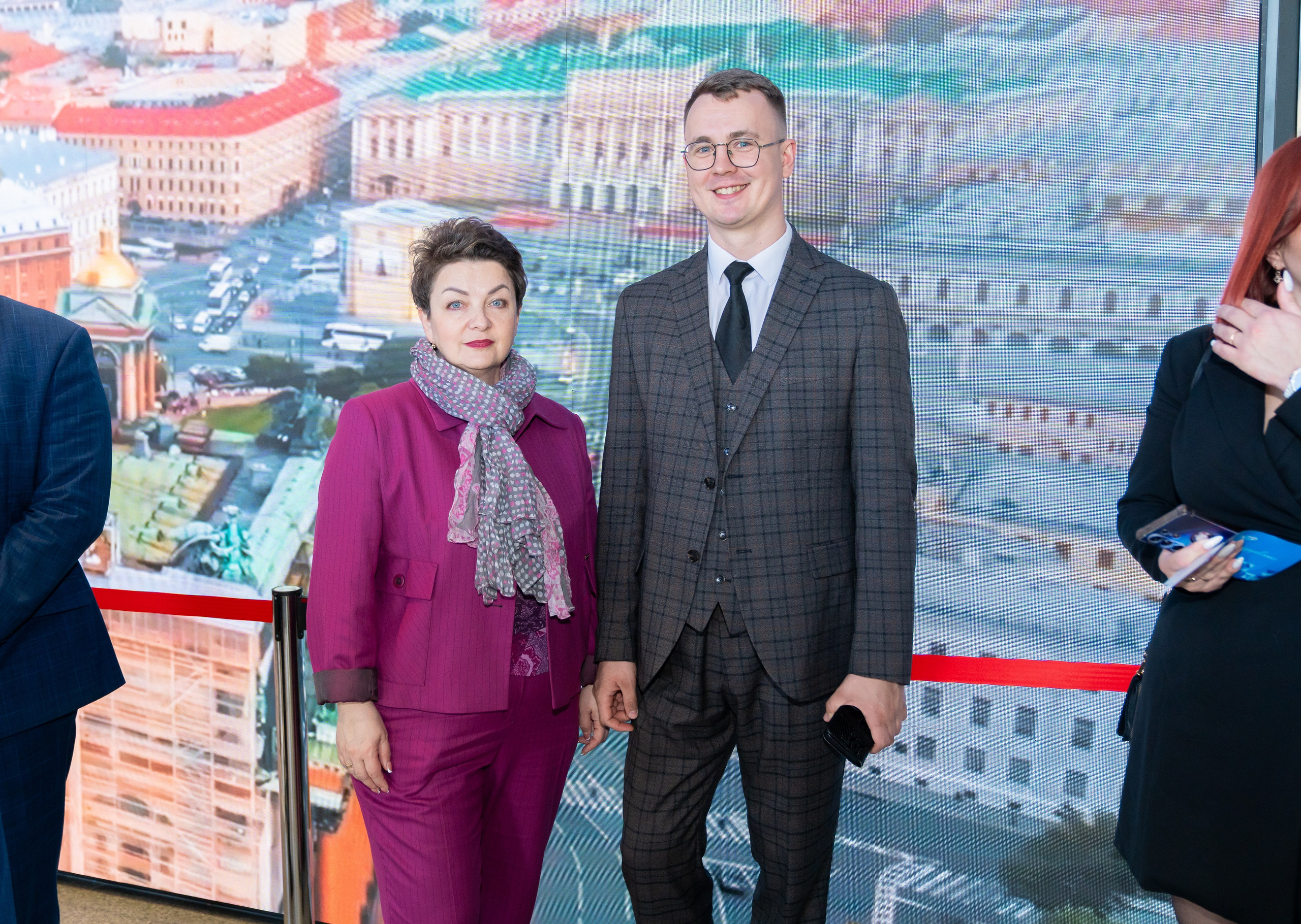 Участники Дня местного самоуправления в Санкт-Петербурге. Женщина в малиновом костюме и мужчина в сером клетчатом костюме. Фотография Евгения Мальцева.