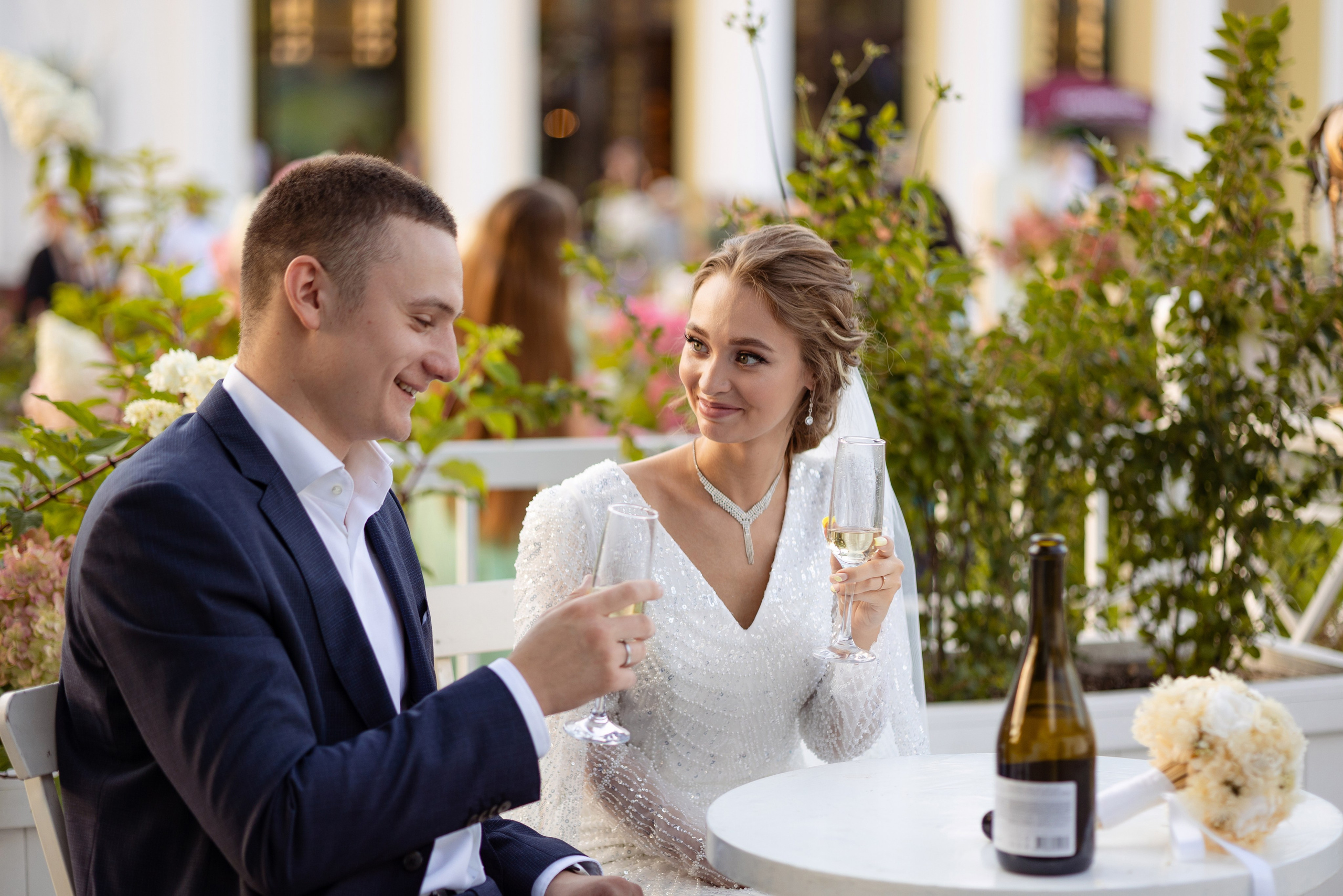 Молодые сидят за столом с фужерами в руках.