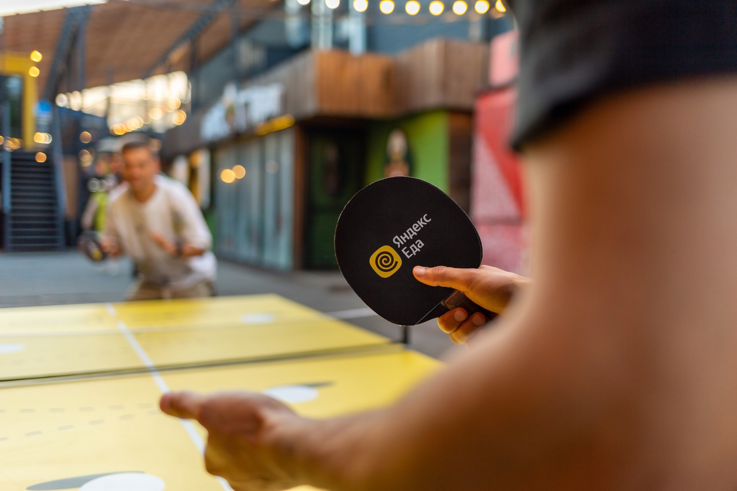 Рука с ракеткой крупно. Ракетка для настольного тенниса в руках. Черная ракетка.