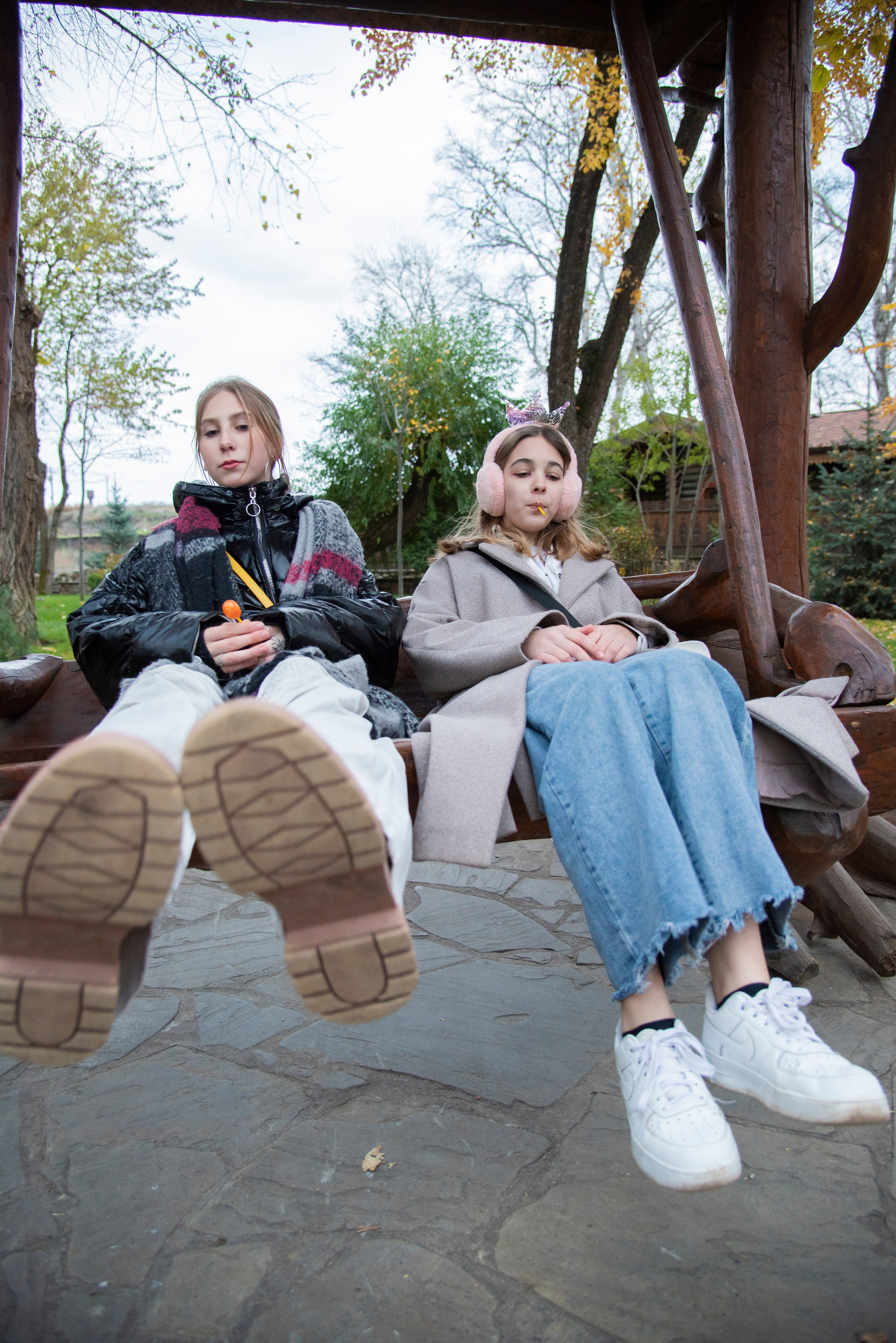 Две девушки на качелях, широкий угол, ноги, обувь, джинсы, парк лога. осень