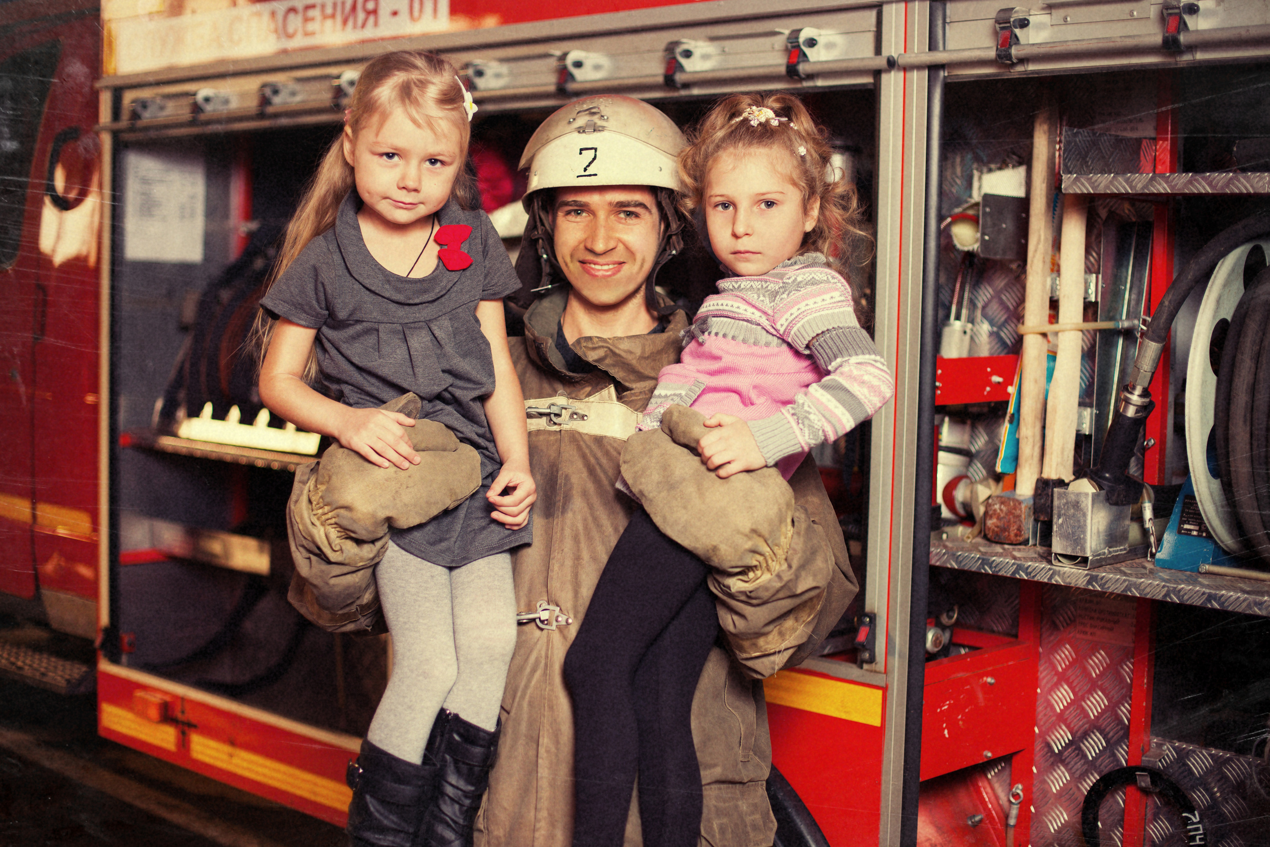 пожарный спасает детей от пожара и выносит их на руках
