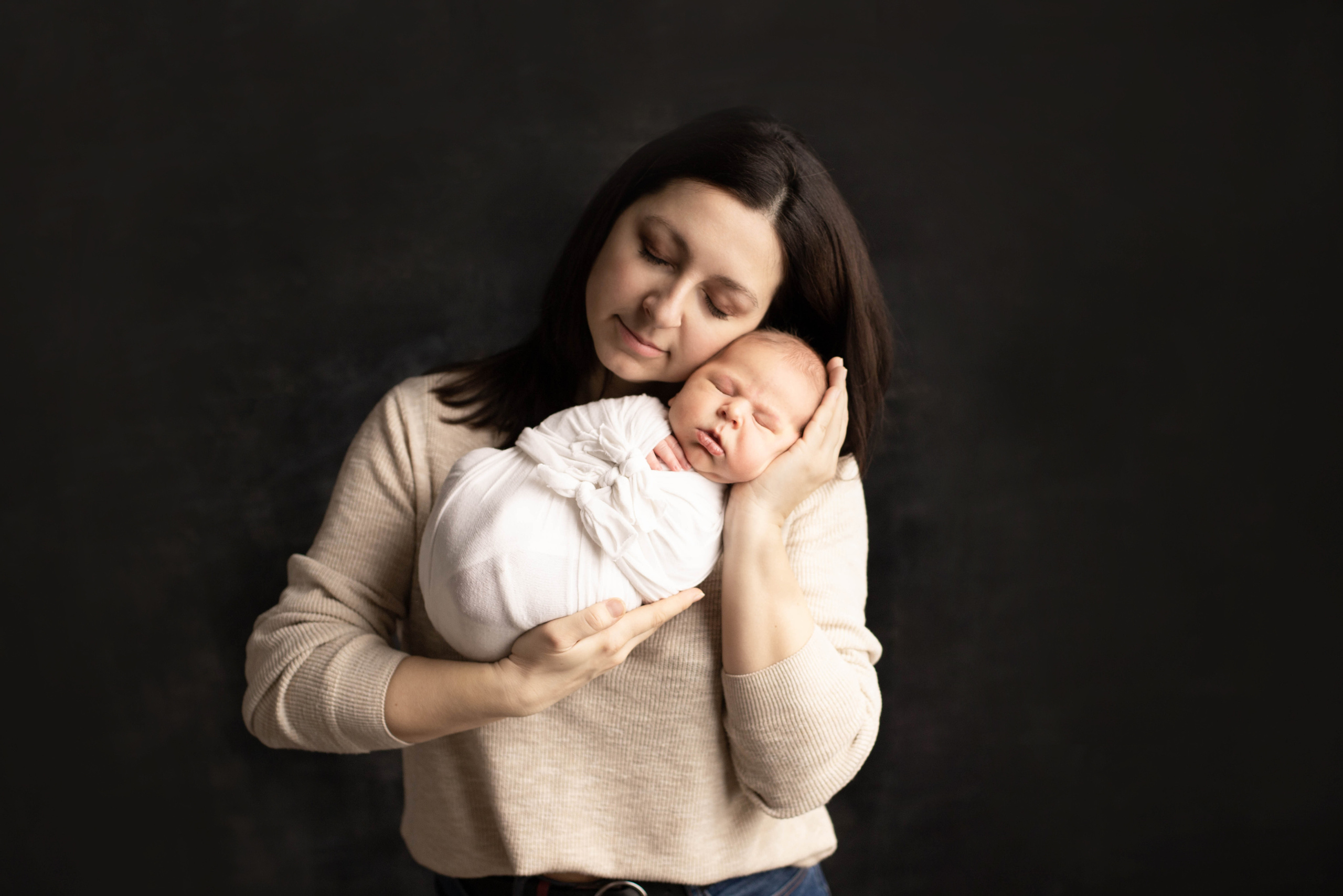 Фотография мамы с новорожденным малышом на руках на темном фоне