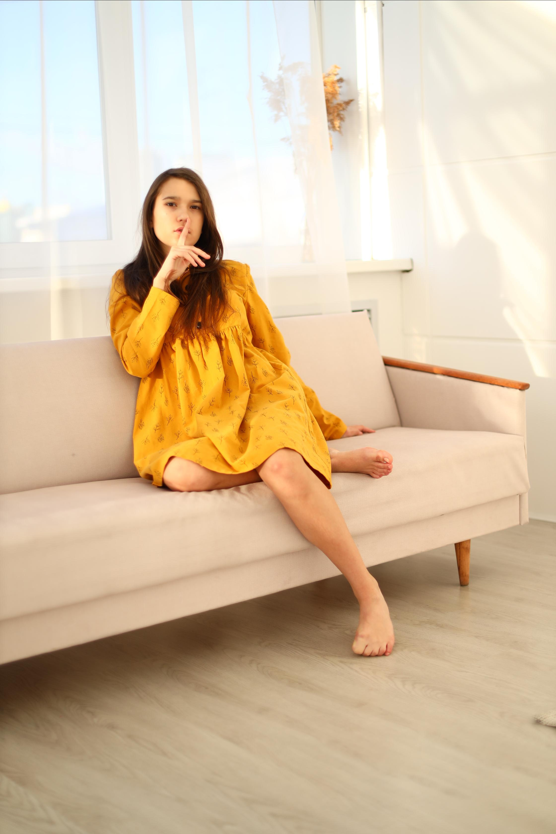 Девушка в жёлтом платье приложила палец к губам