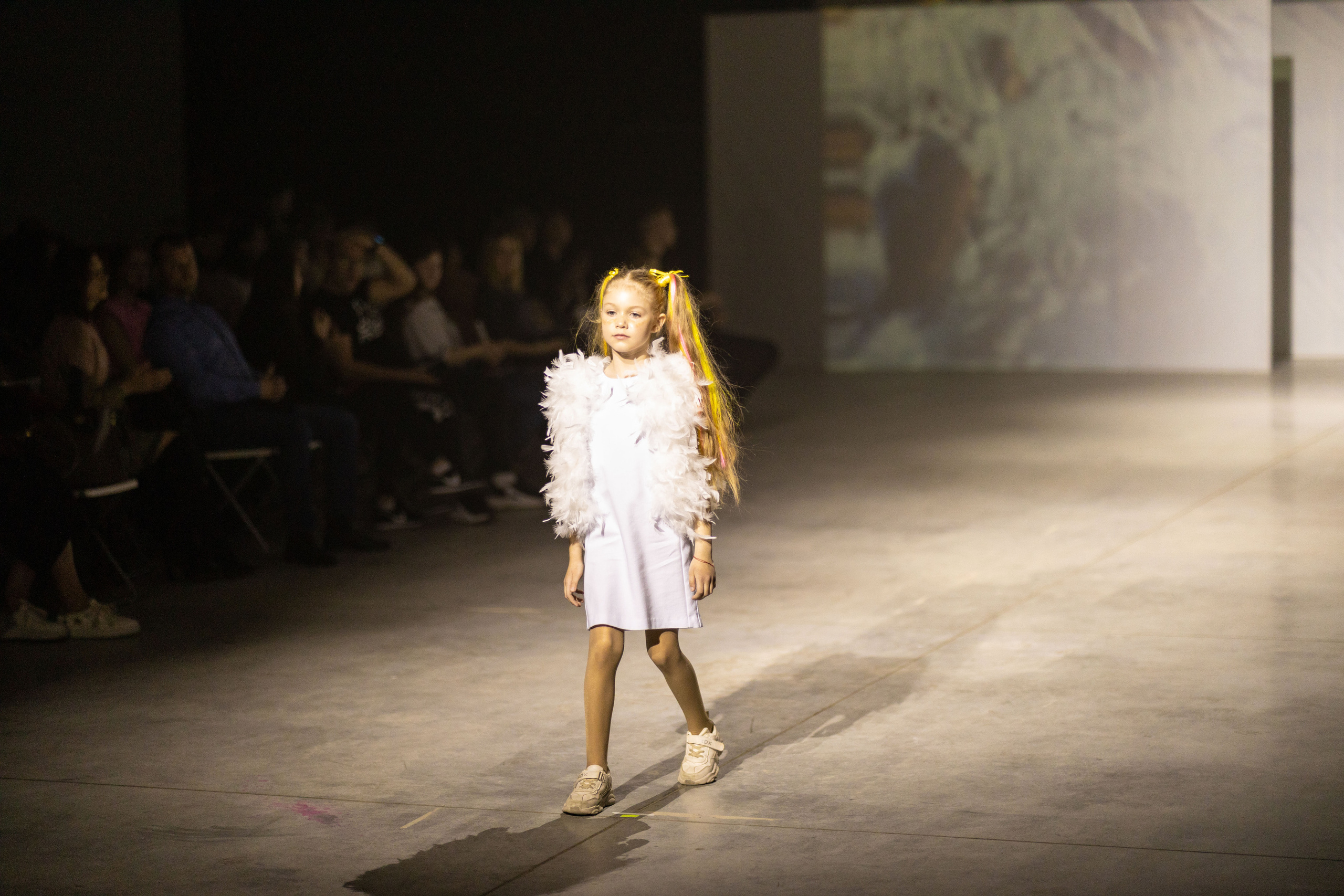 Модный показ. Платья от demodacomodo. Девочка в красном платье трогает ёлку. Модель Алиса Алексееву на модном показе в платье