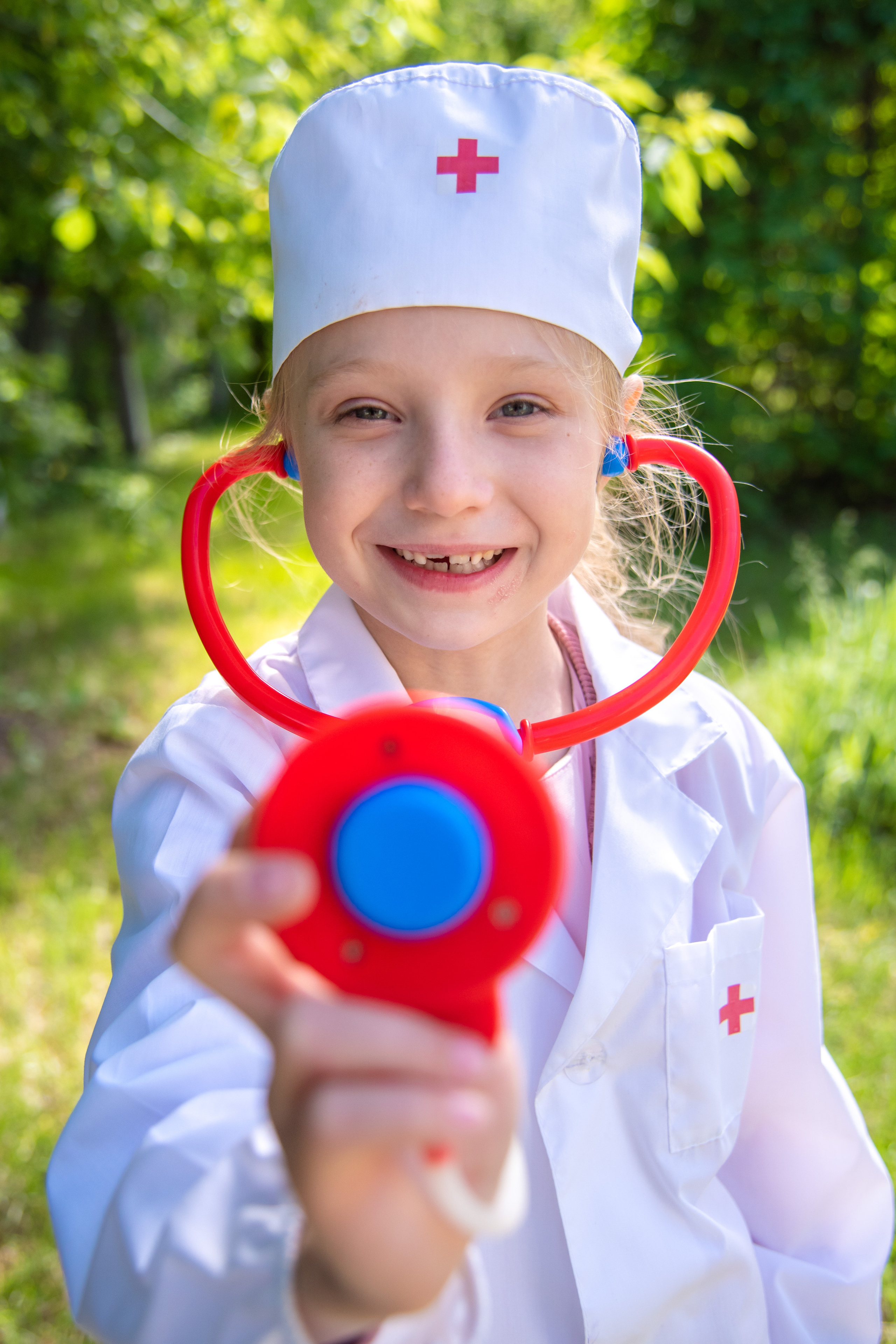 Девочка в одежде доктора в солнечный летний денек