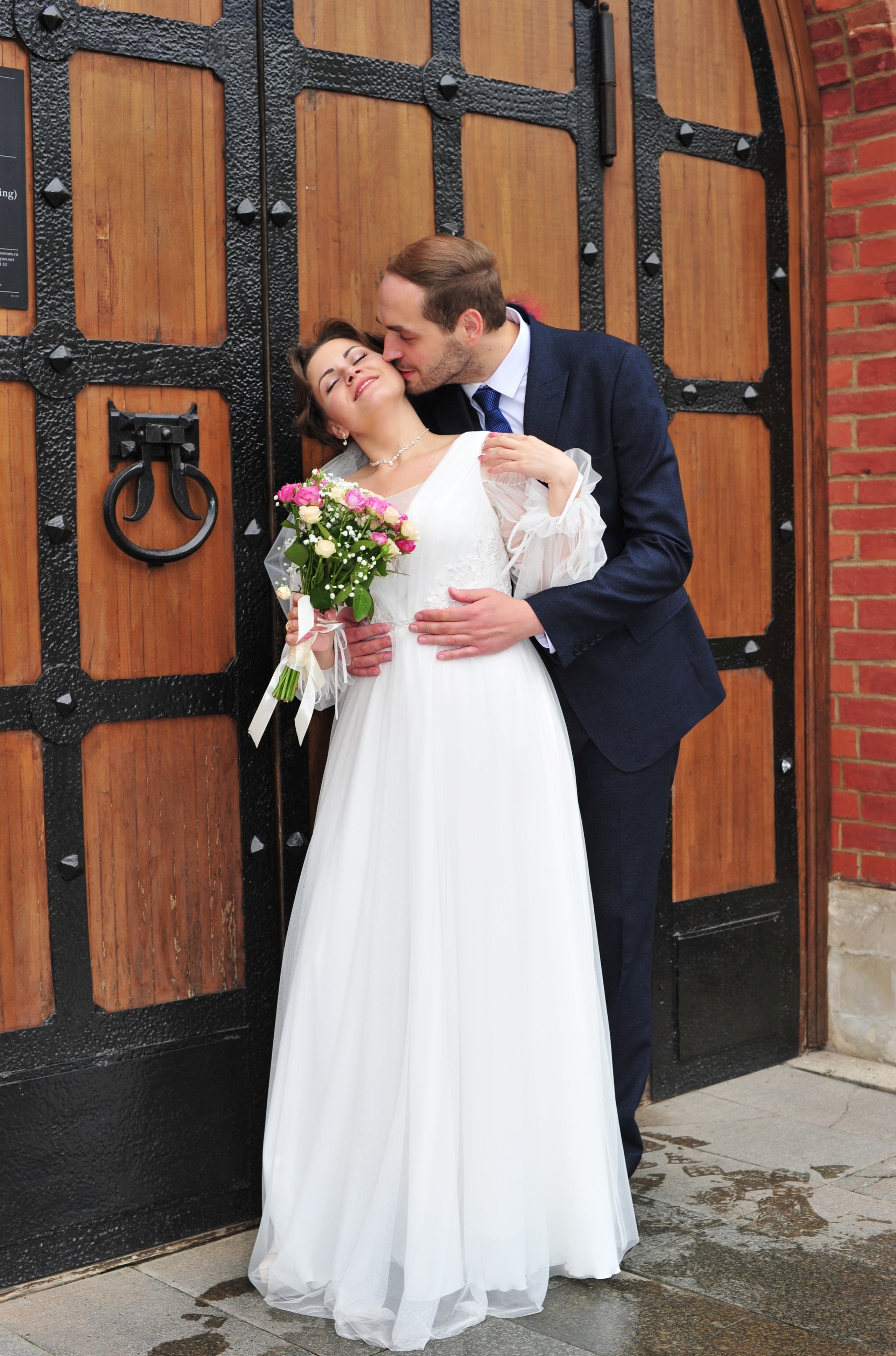Свадьба в Царицыно пасмурным летним днем, поцелуй новобрачных на фоне старинной деревянной двери 