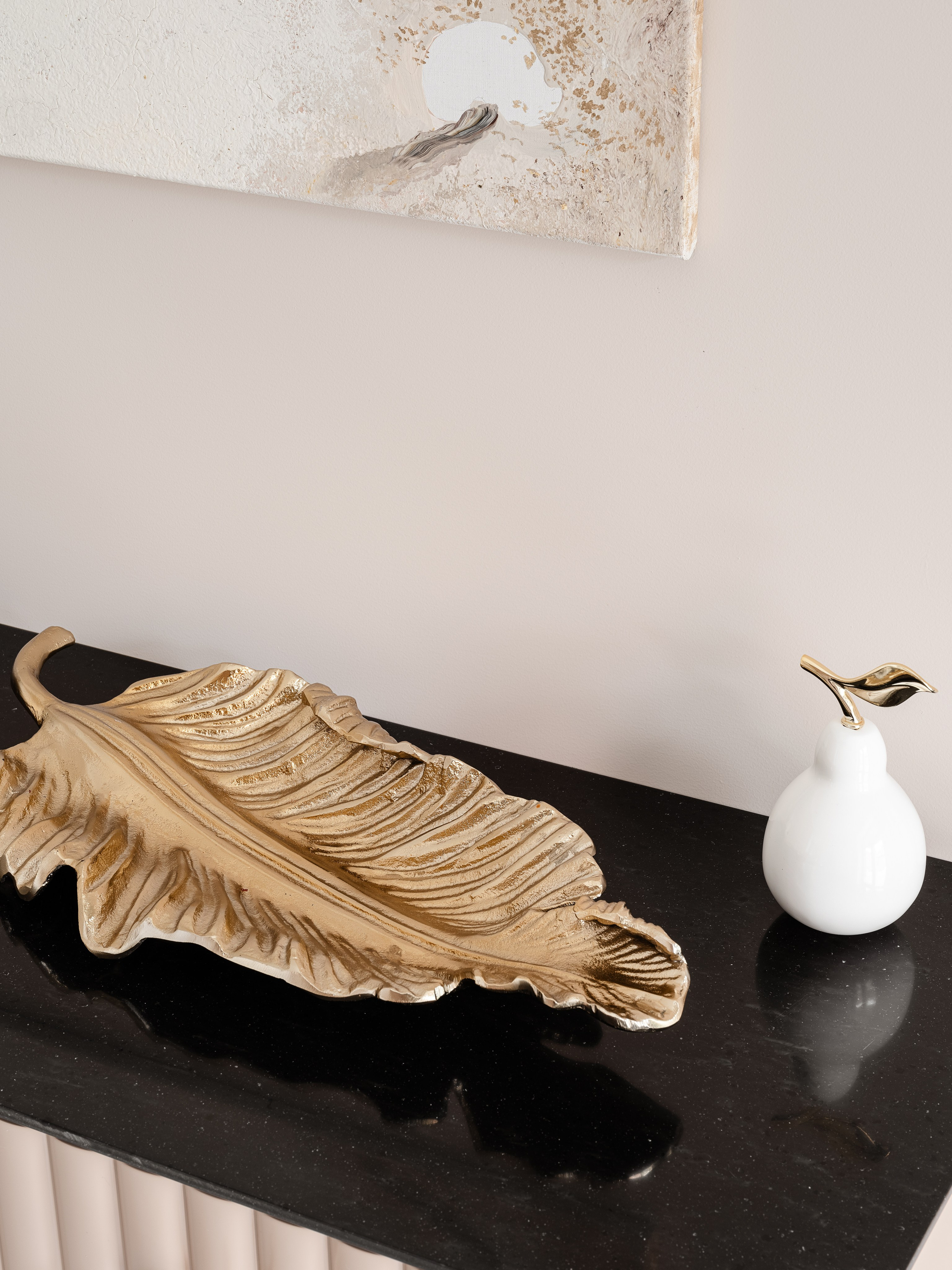 Элегантный интерьерный декор в современном стиле: консоль с чёрной столешницей, золотой поднос в форме листа и белая статуэтка с золотым акцентом. Дизайн Евгении Ермошиной, фото интерьера Сергея Денисенко.