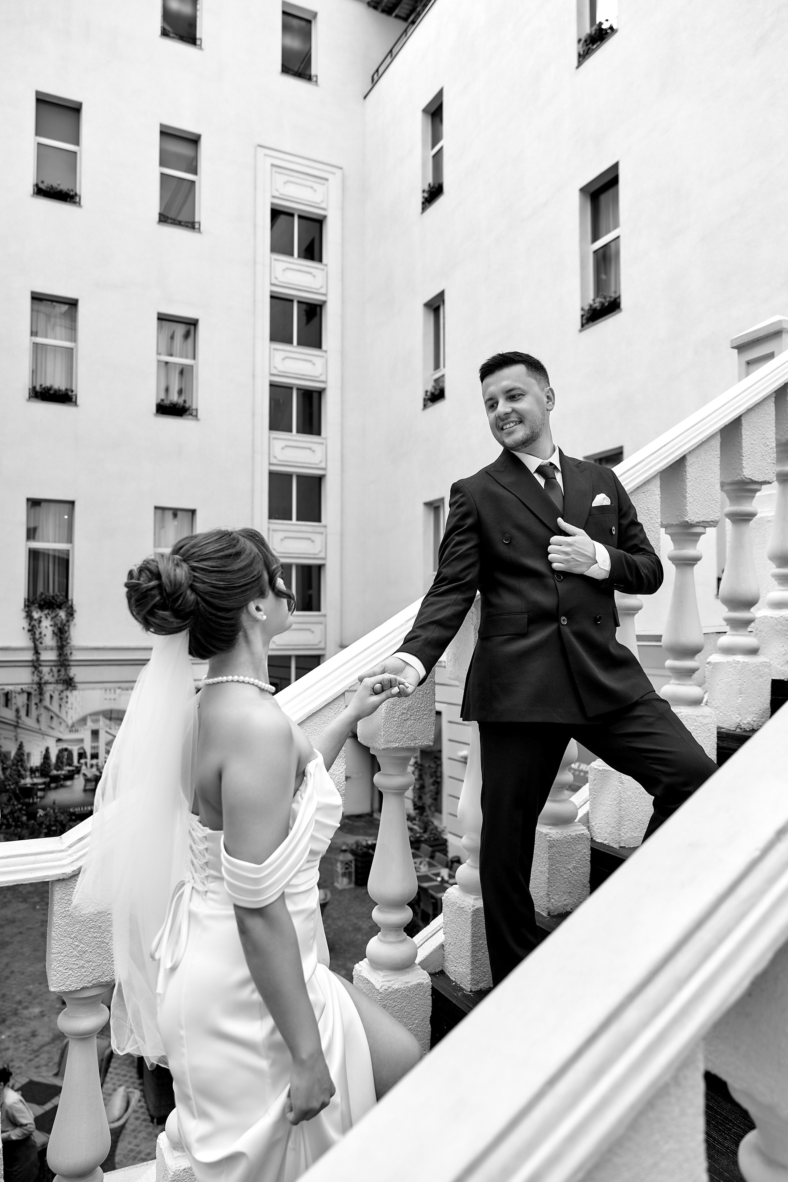 Первый взгляд жениха на невесту на свадьбе. Искренние эмоции молодоженов во время встречи у лестницы в дворике с красными цветами. Свадебная фотография лучшего свадебного фотографа Ульяновска Елены Орешиной.