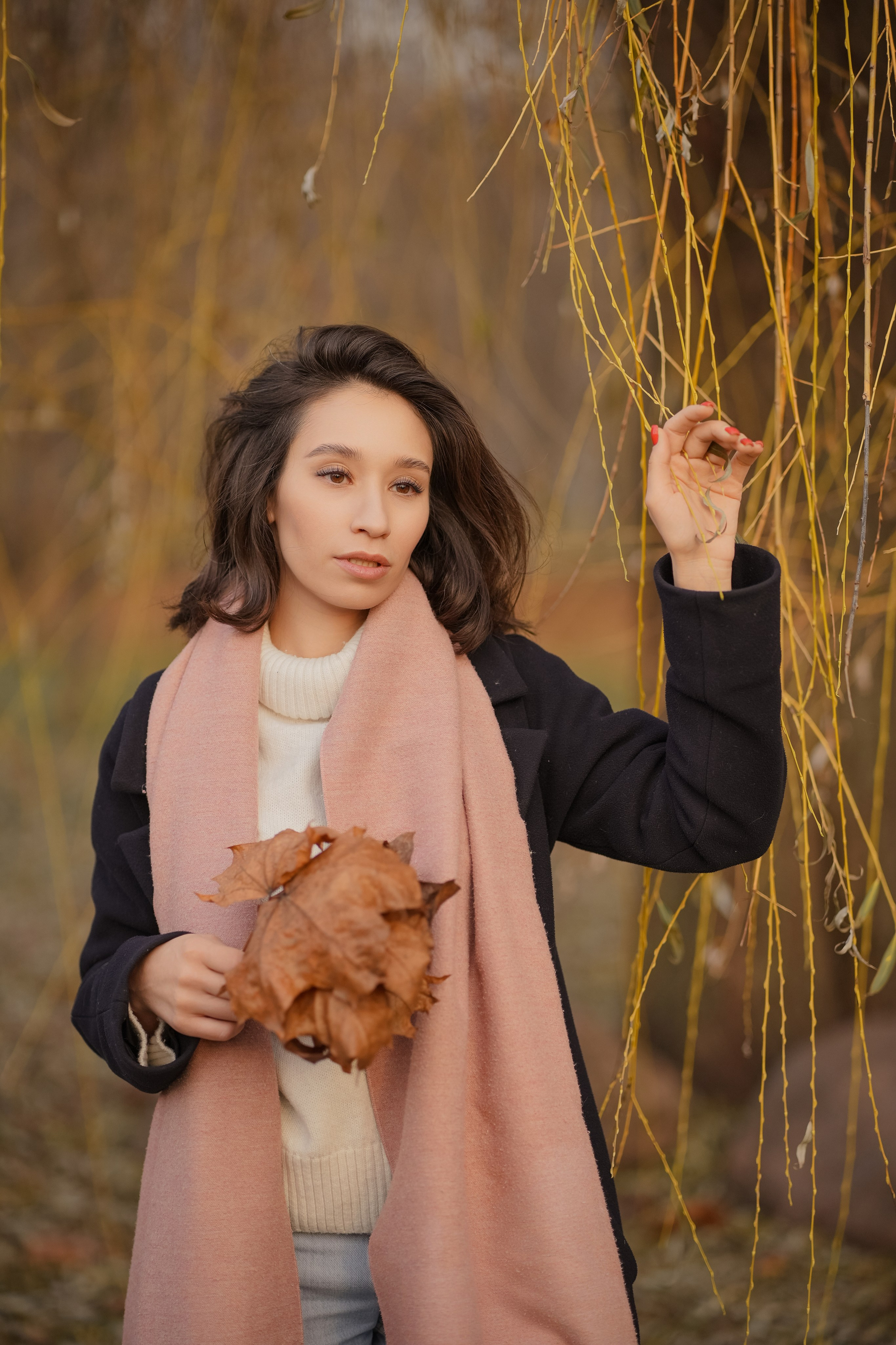 молодая девушка с темными волосами гуляет по осеннему парку