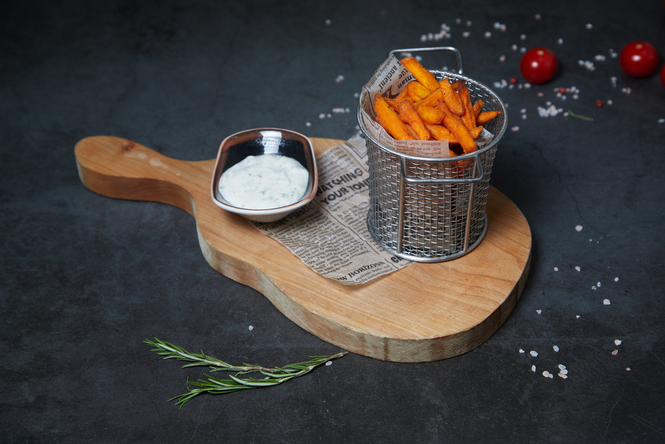 Батат фри в металлической корзинке с соусом на деревянной доске