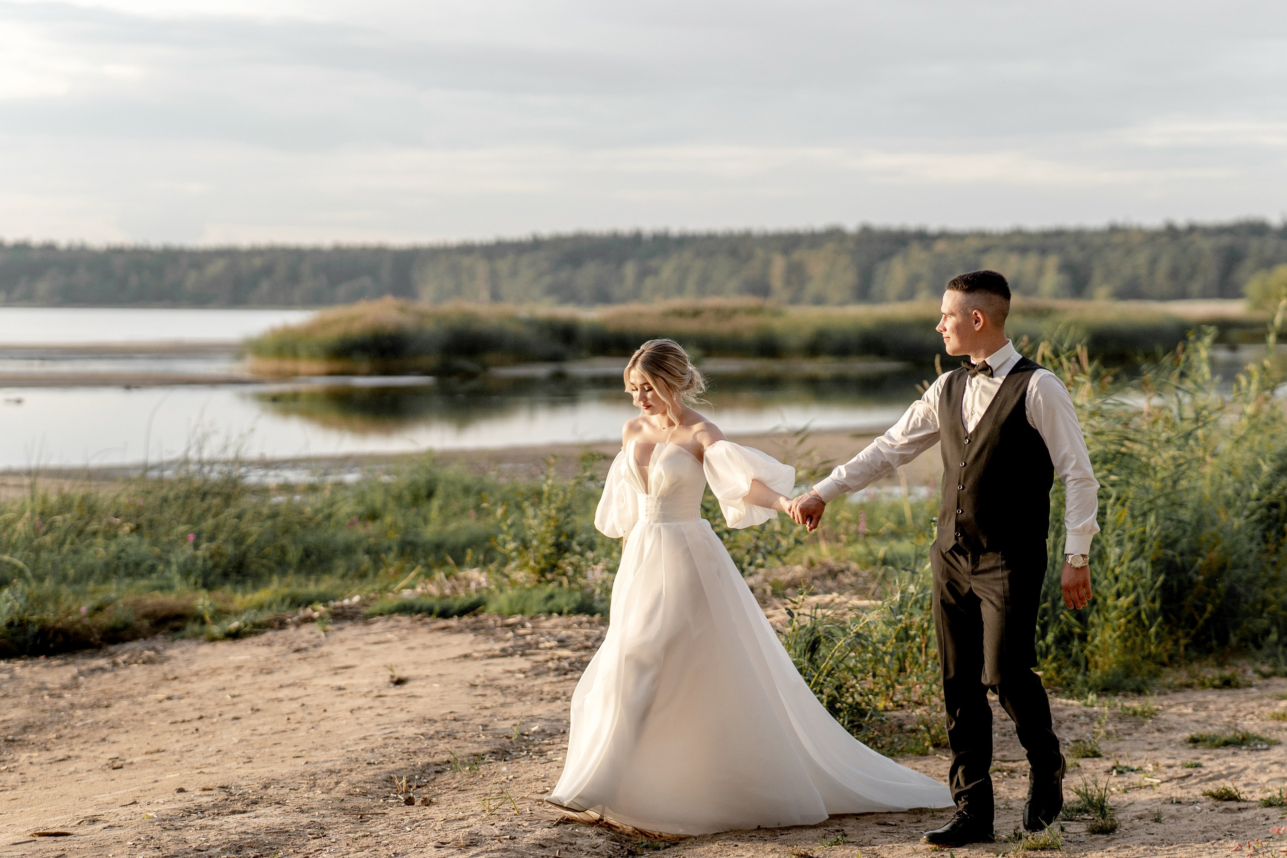 Жених и невеста идут по песку на берегу Финского залива