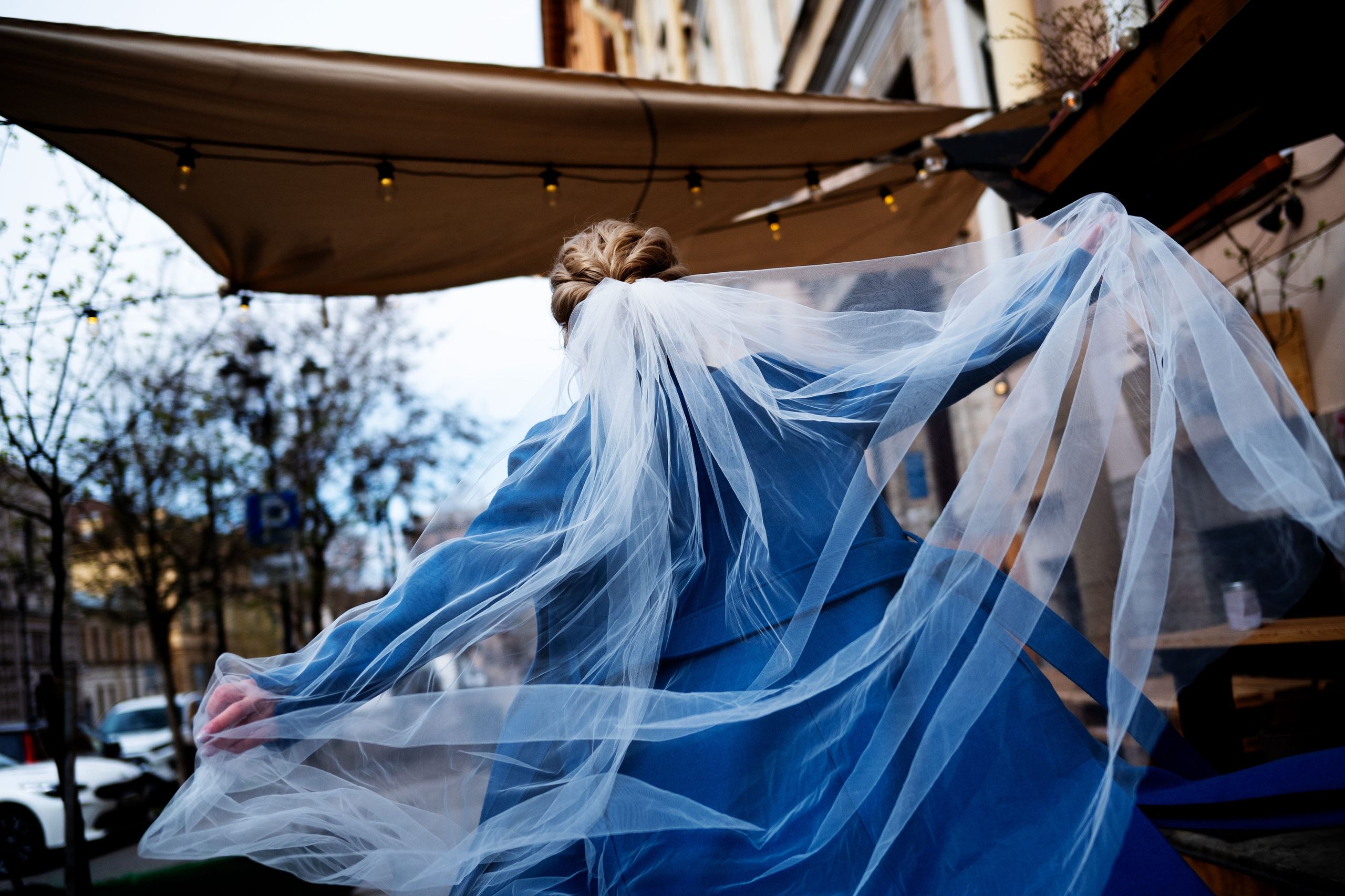 Фата невесты развевается на ветру на фоне пальто