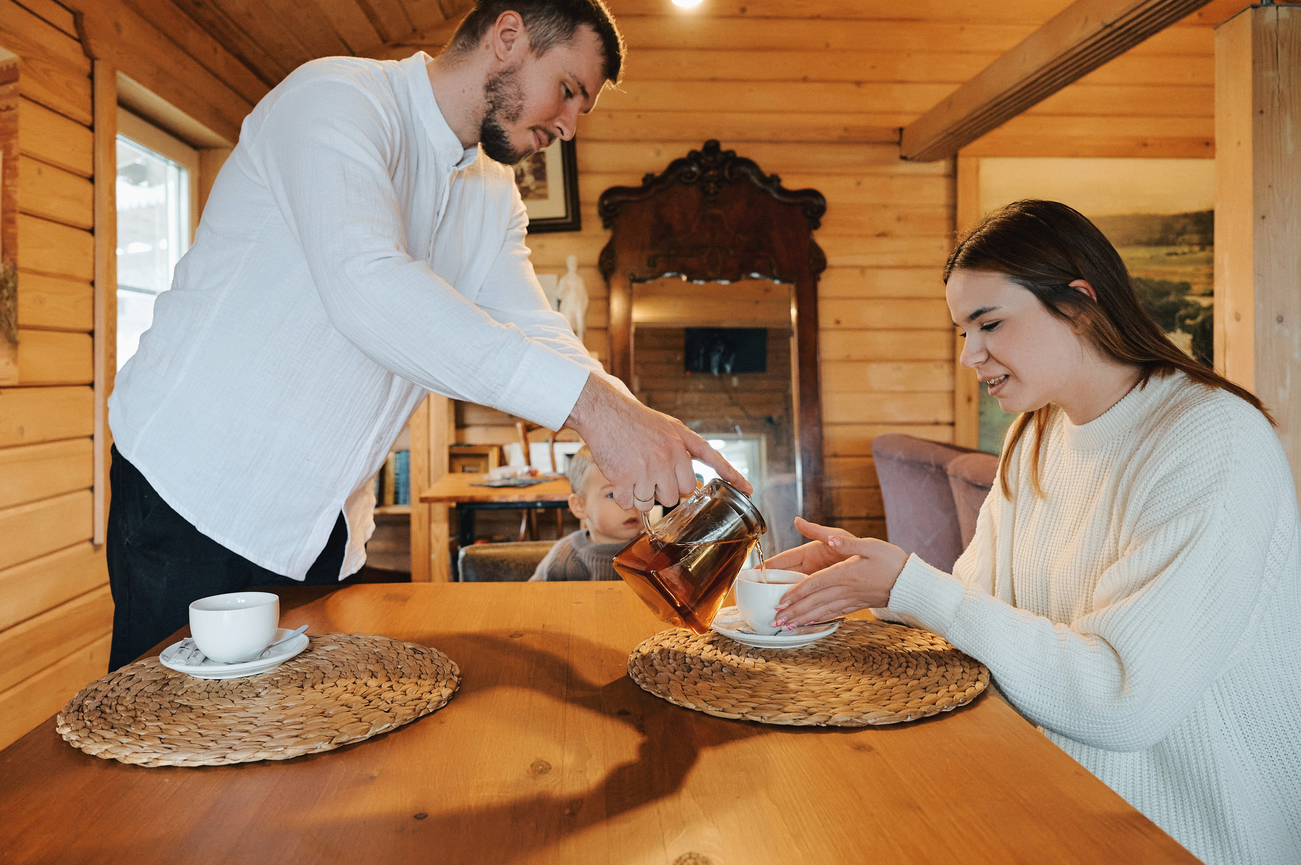 папа наливает чай маме за деревянным столом, уютный интерьер