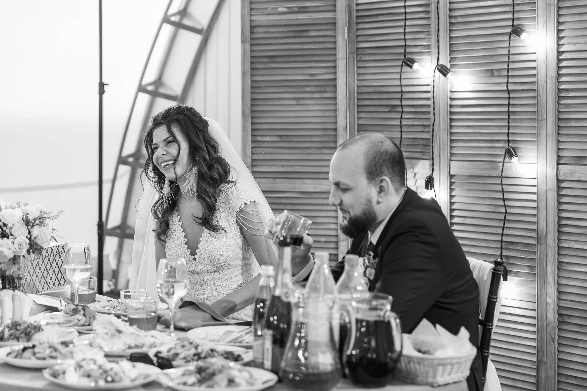 Невеста и жених выпивают за свадебным столом