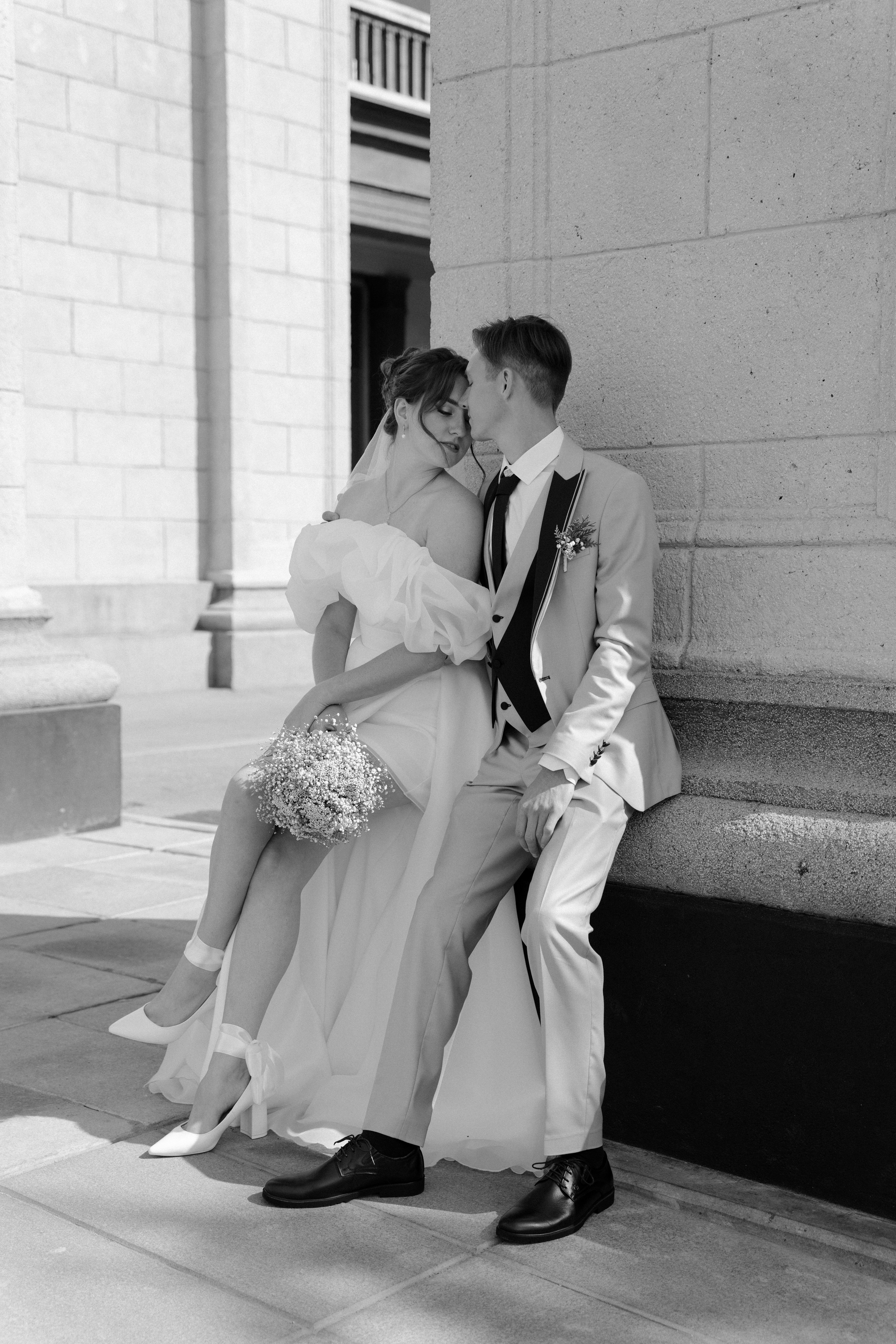 Жених и невеста у театра сидят у колонны