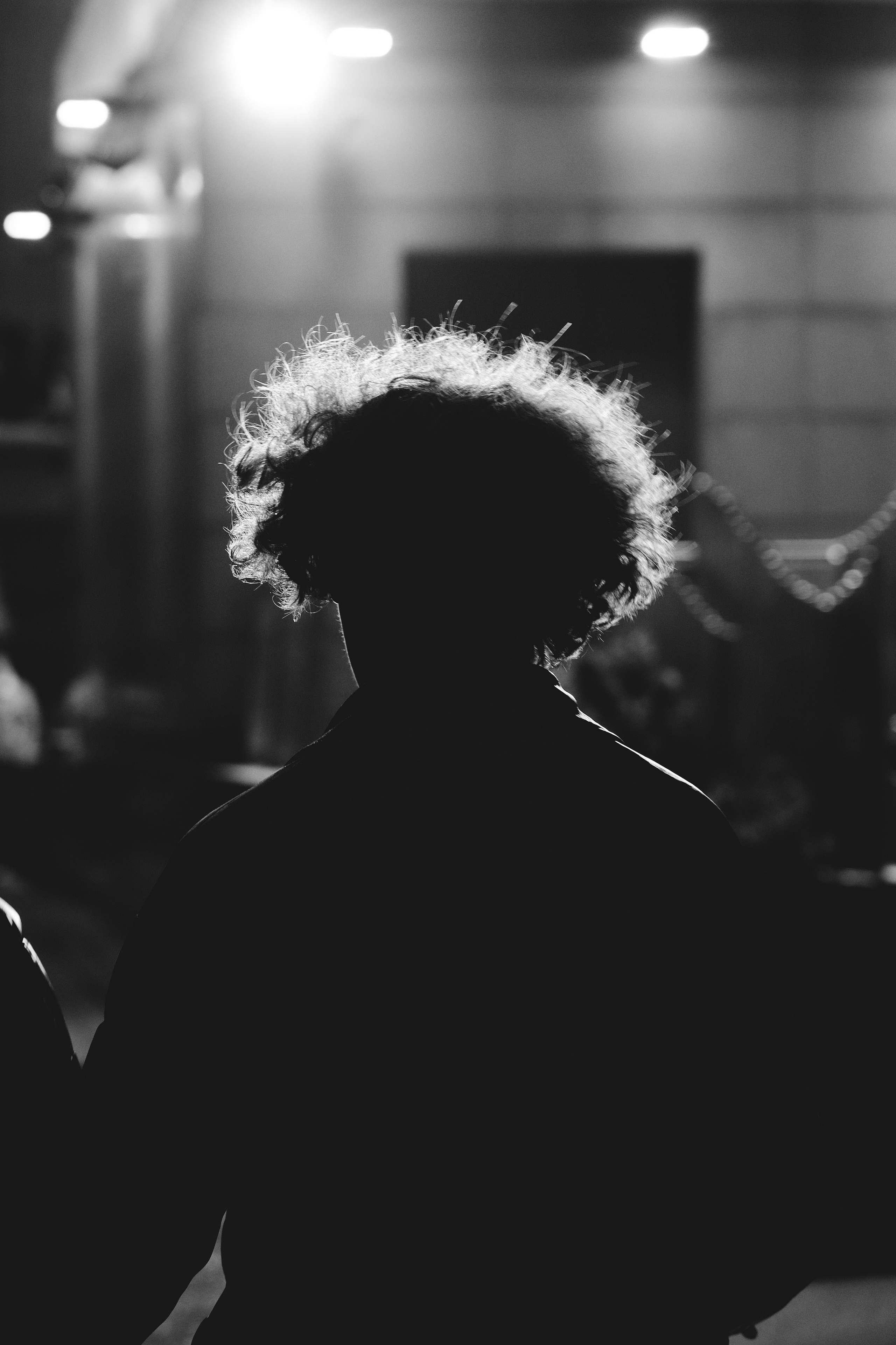 силуэт молодого человека и его подсвеченные кудрявые волосы