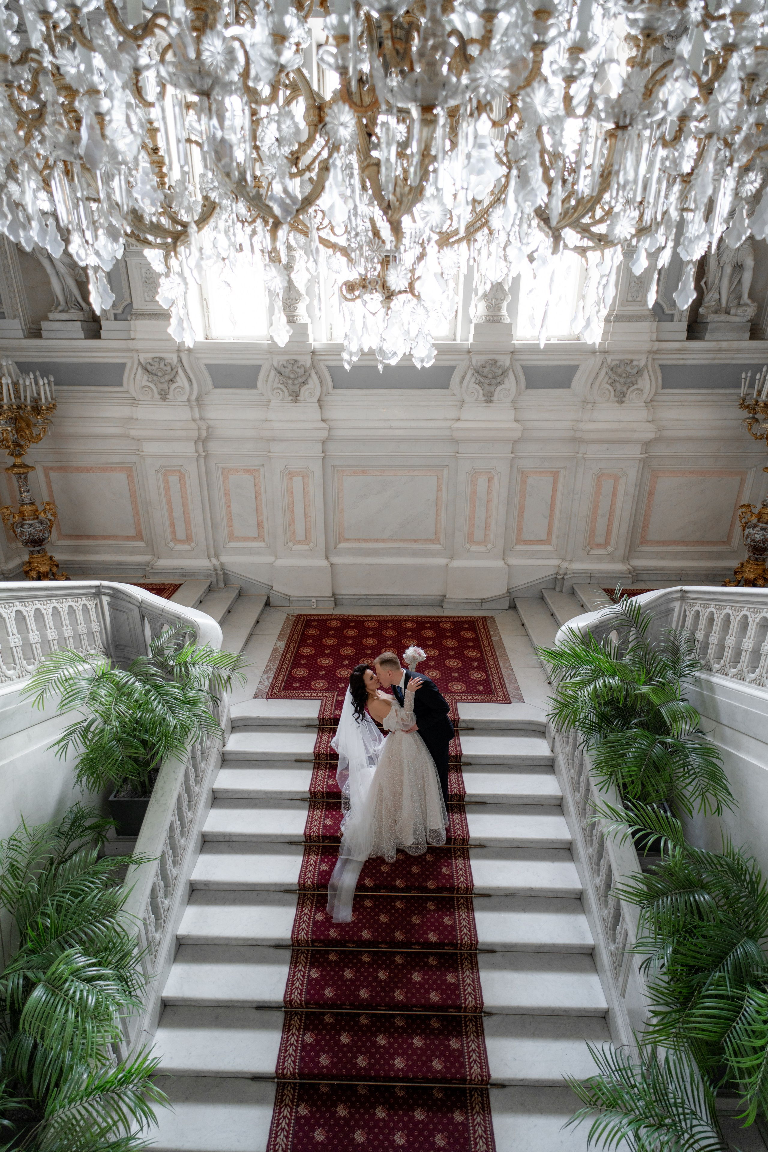 Пара поднимаются по парадной лестнице дворца на свадебной фотосессии в Юсуповском дворце в Санкт-Петербурге