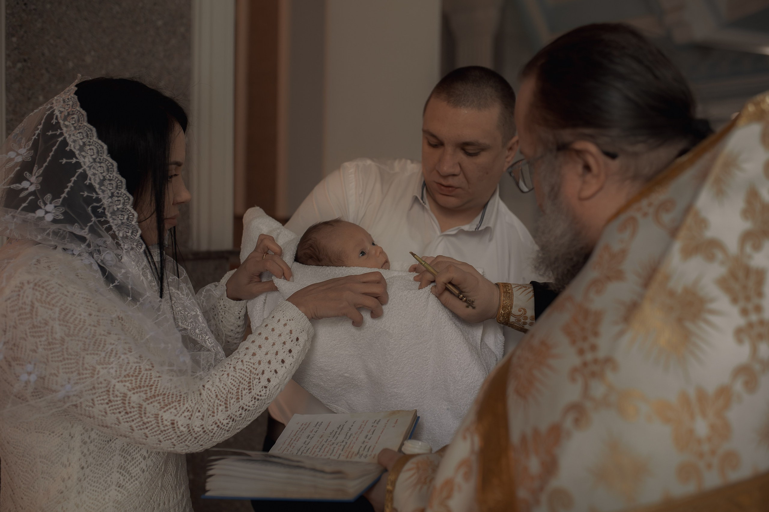 Иеромонах Михаил (Столяров) помазывает ребенка освященным маслом перед Крещением в Ташкенте