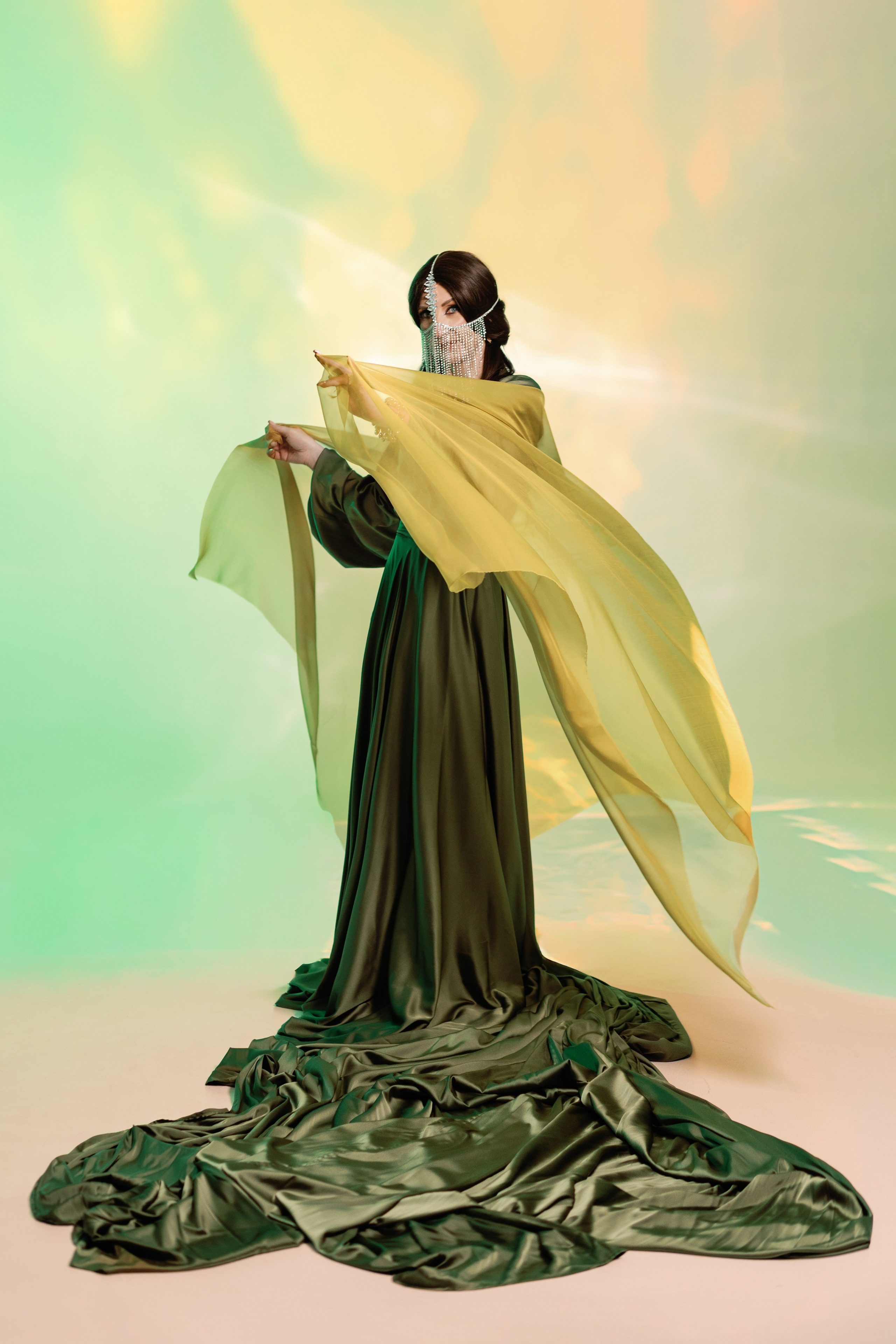 На фотографии изображена девушка в платье со шлейфом и восточными украшениями на лице в сутдии, фотосессия в восточном стиле