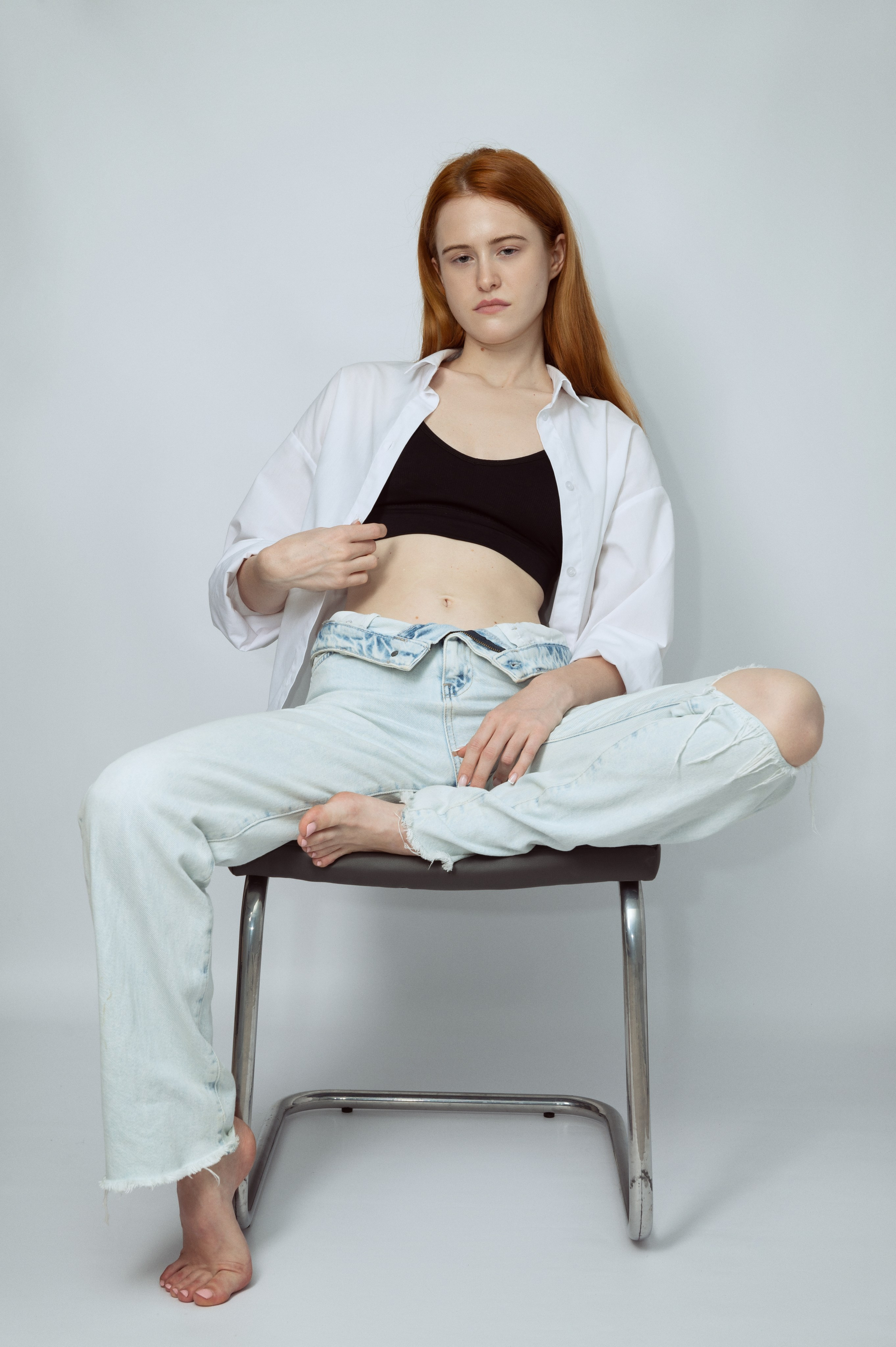 Рыжеволосая девушка-модель в белой рубашке и светлых джинсах на светлом фоне. Модельные тесты