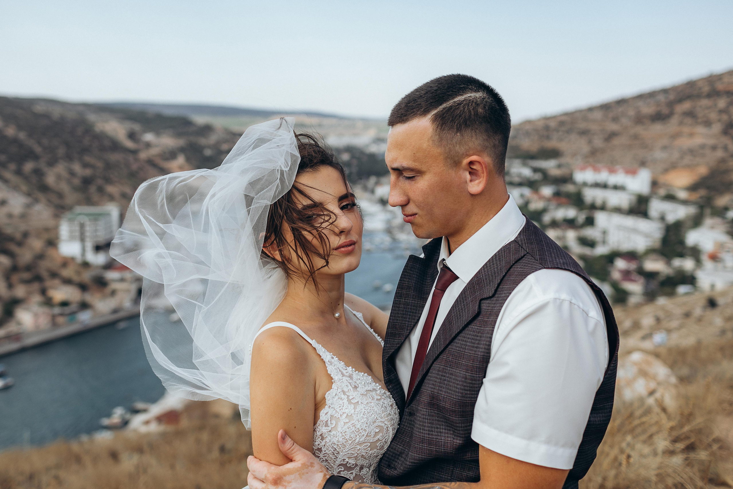 Ветер развивает фоту невесты, в этот момент жених смотрит на нее. Приехали на отдых в Крым.