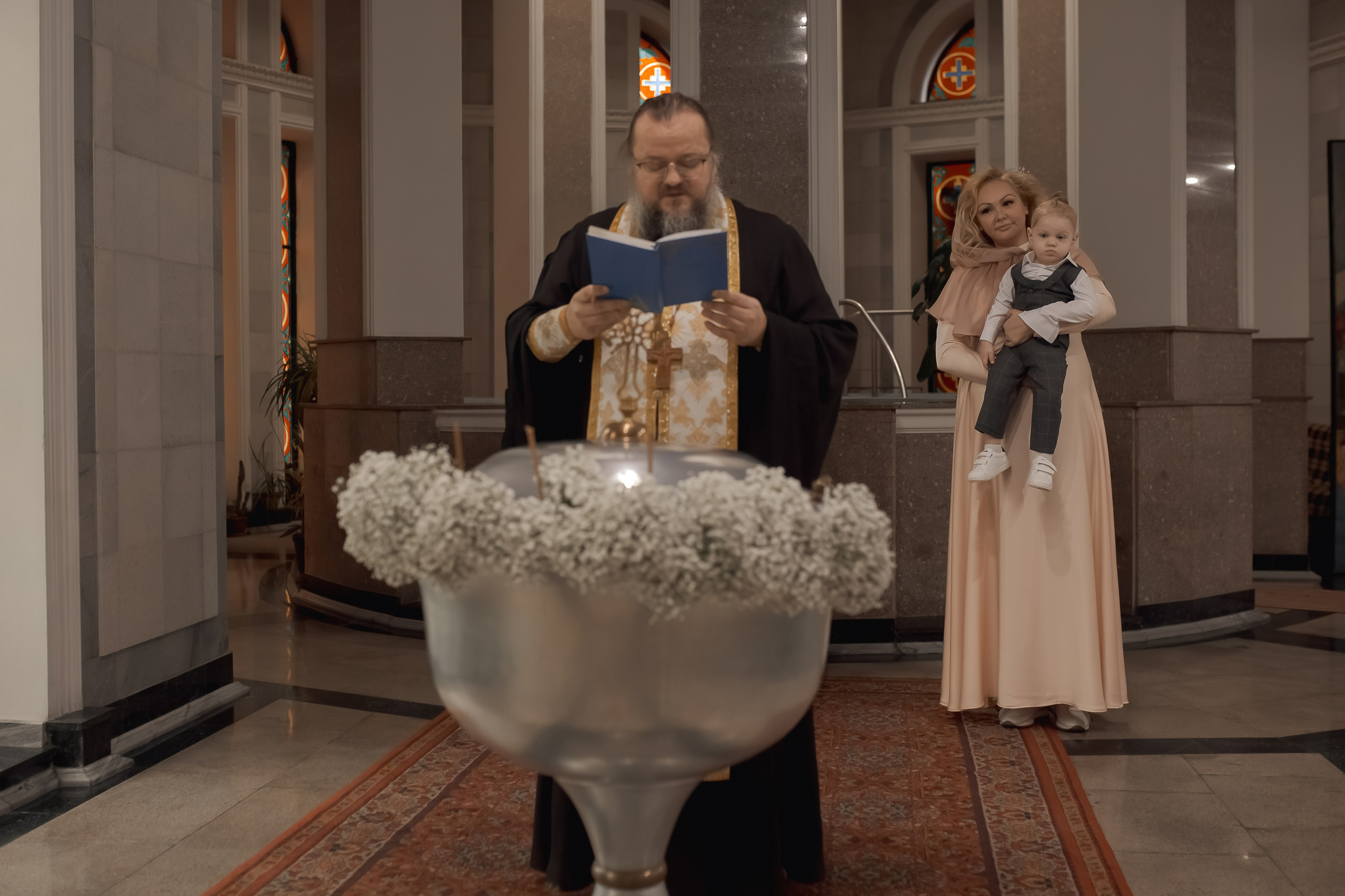 священник перед купелью, украшенной цветами, в Ташкенте