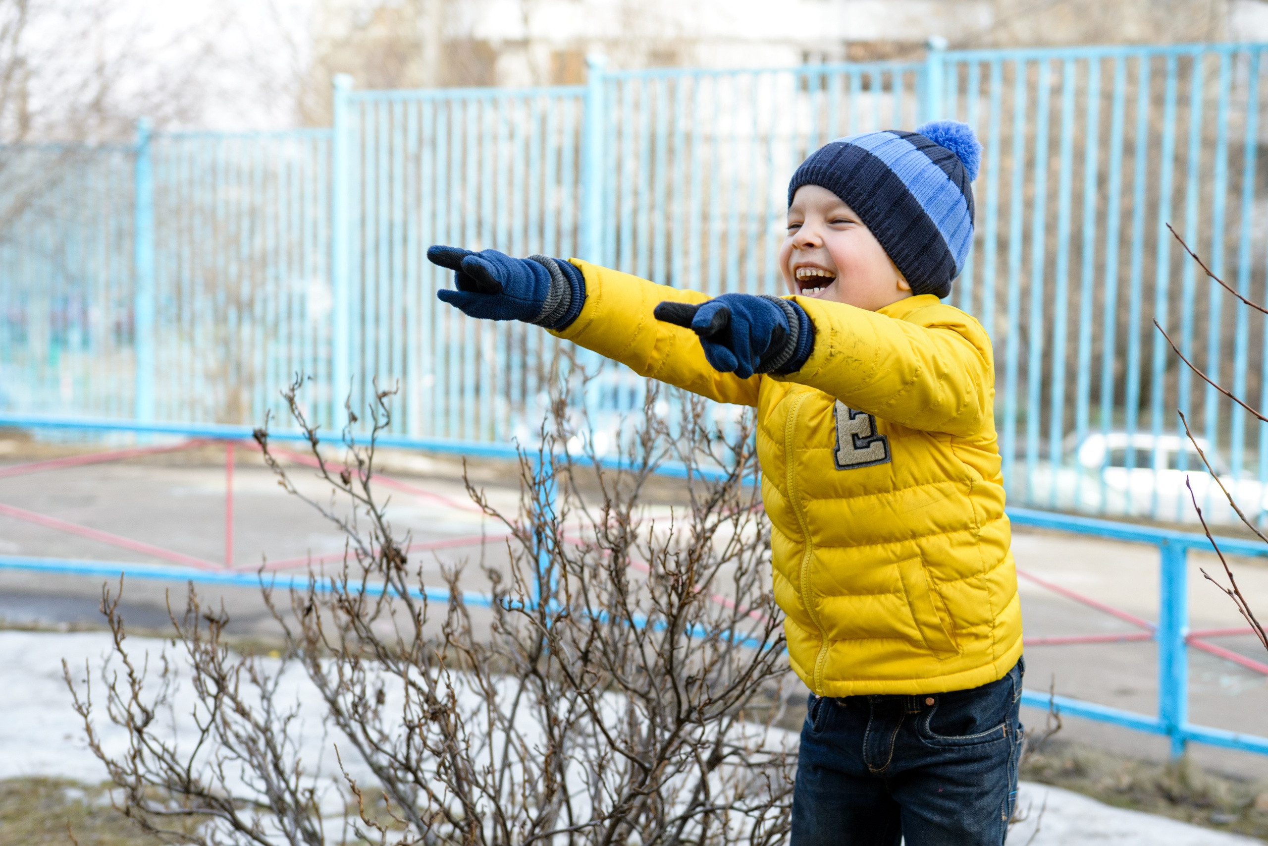 Ребёнок в жёлтой куртке зимой на детской площадке. 