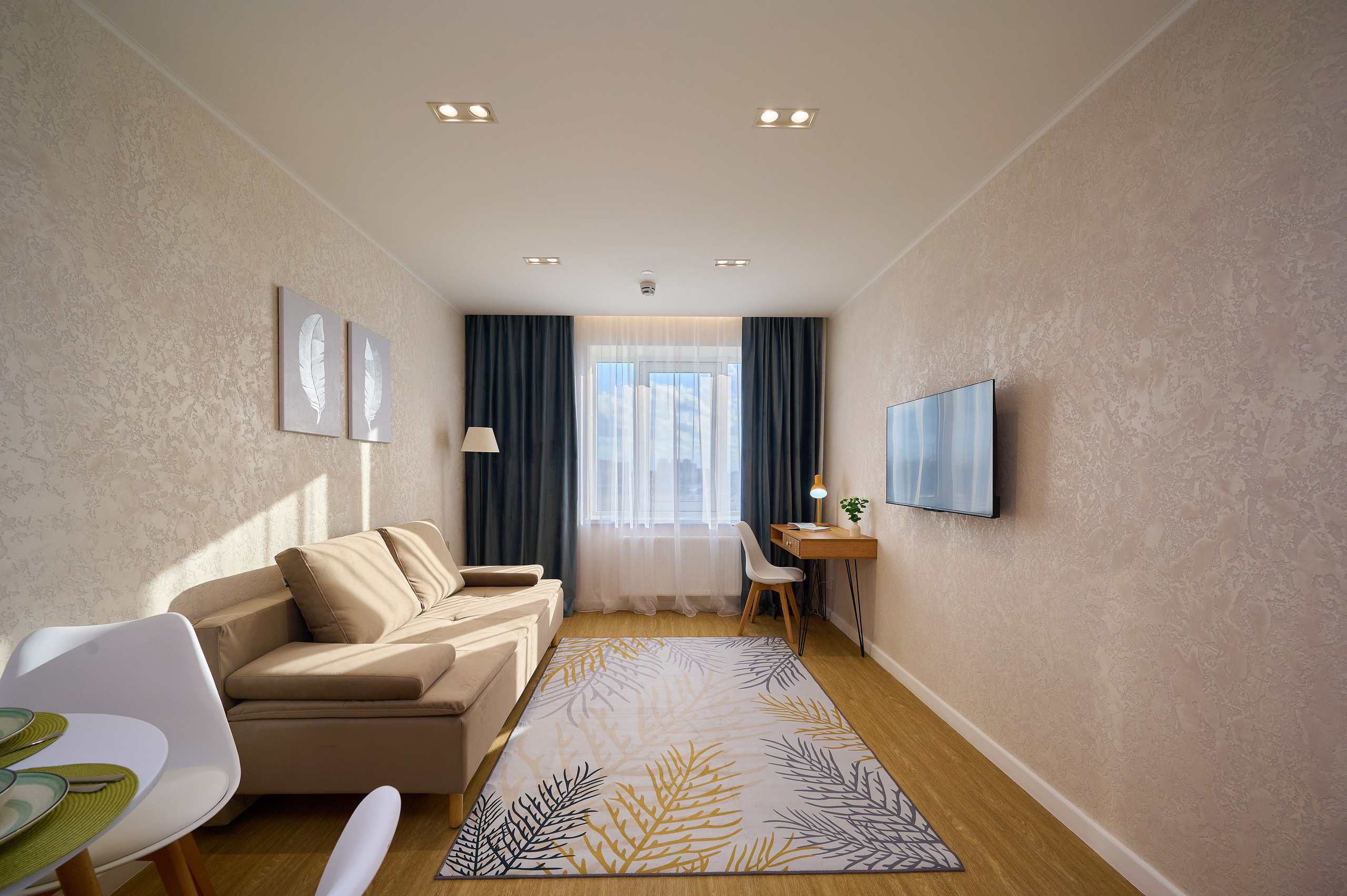 комната светлые оттенки бежевый диван деревянный стол белый стул темные шторы телевизор