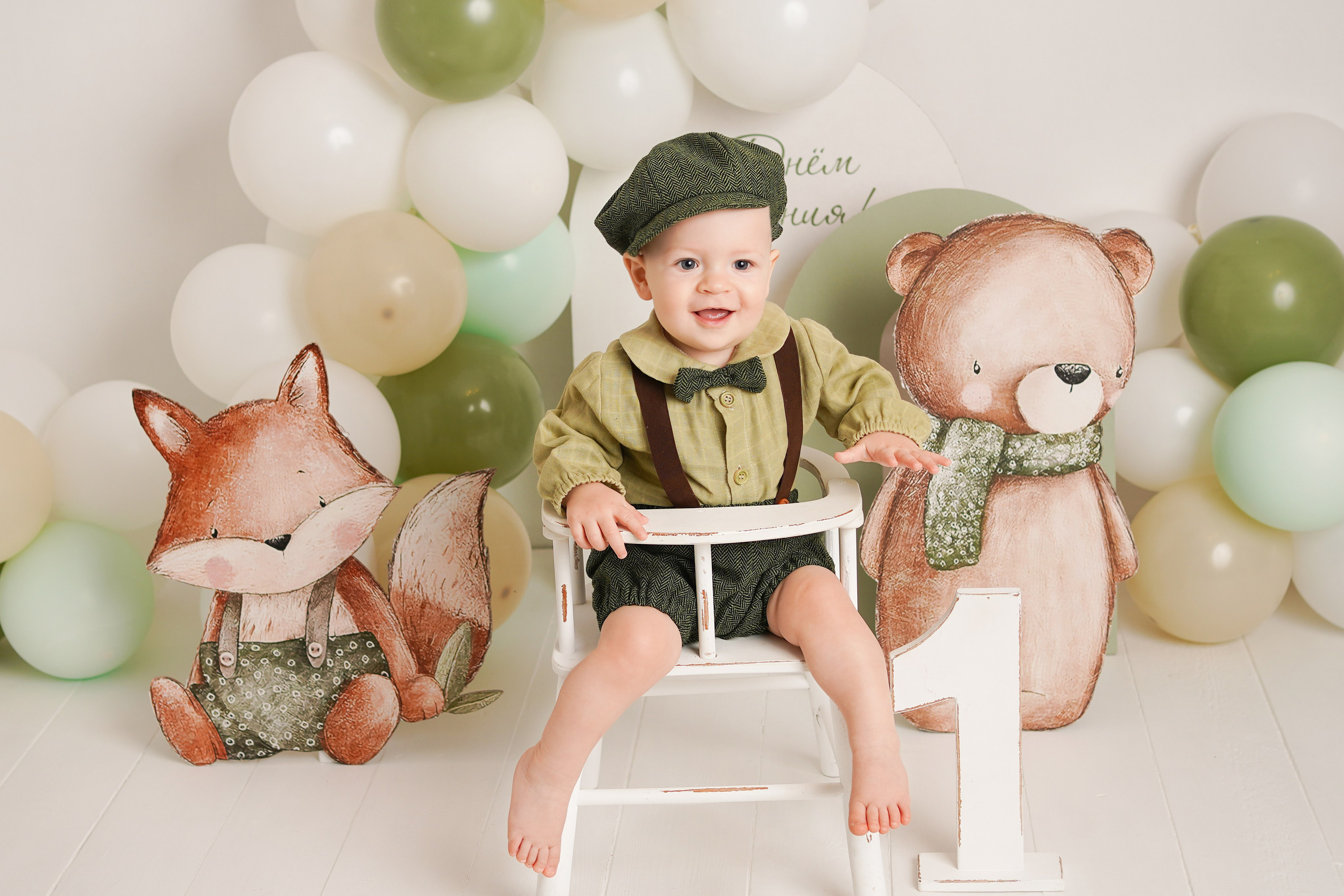 На фотосессии Первый годик  мальчик в нарядном зеленом костюме 