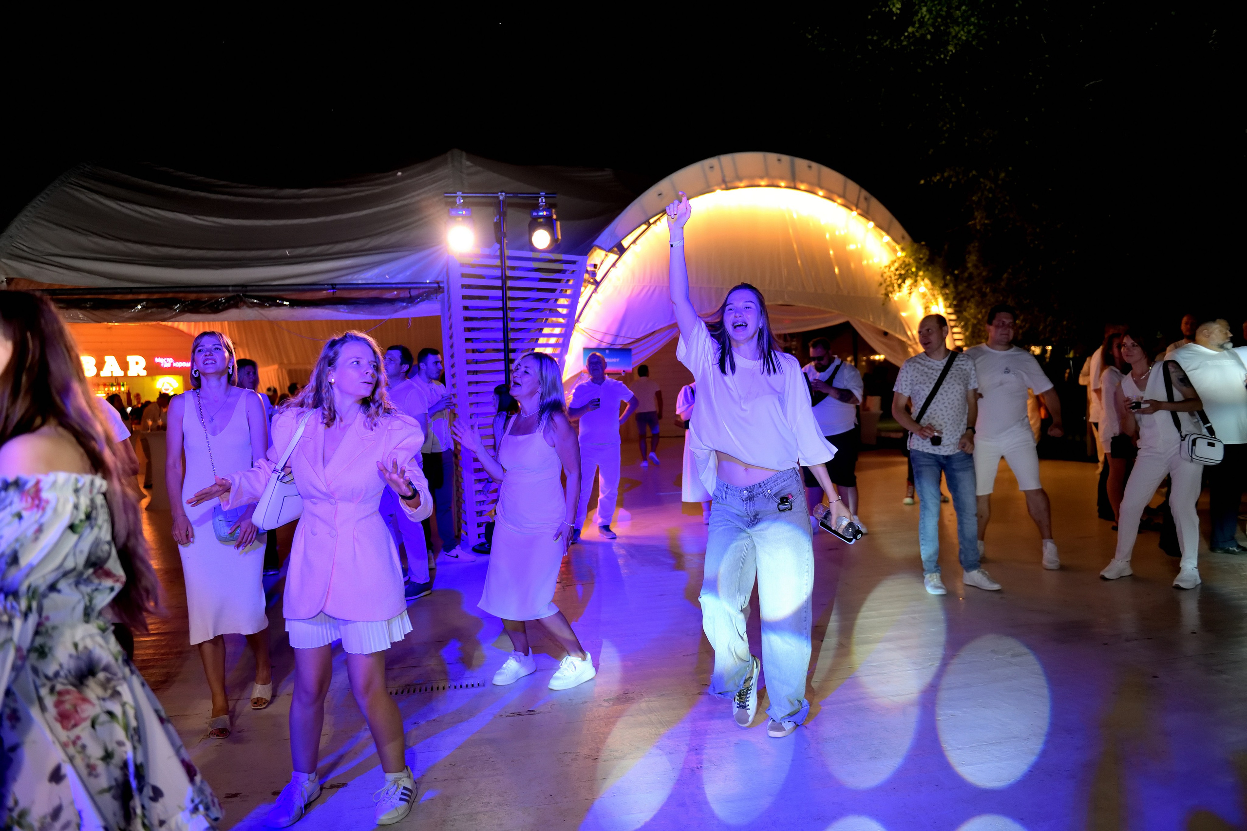 "Счастливые люди танцуют в белом  на летнем корпоративе".