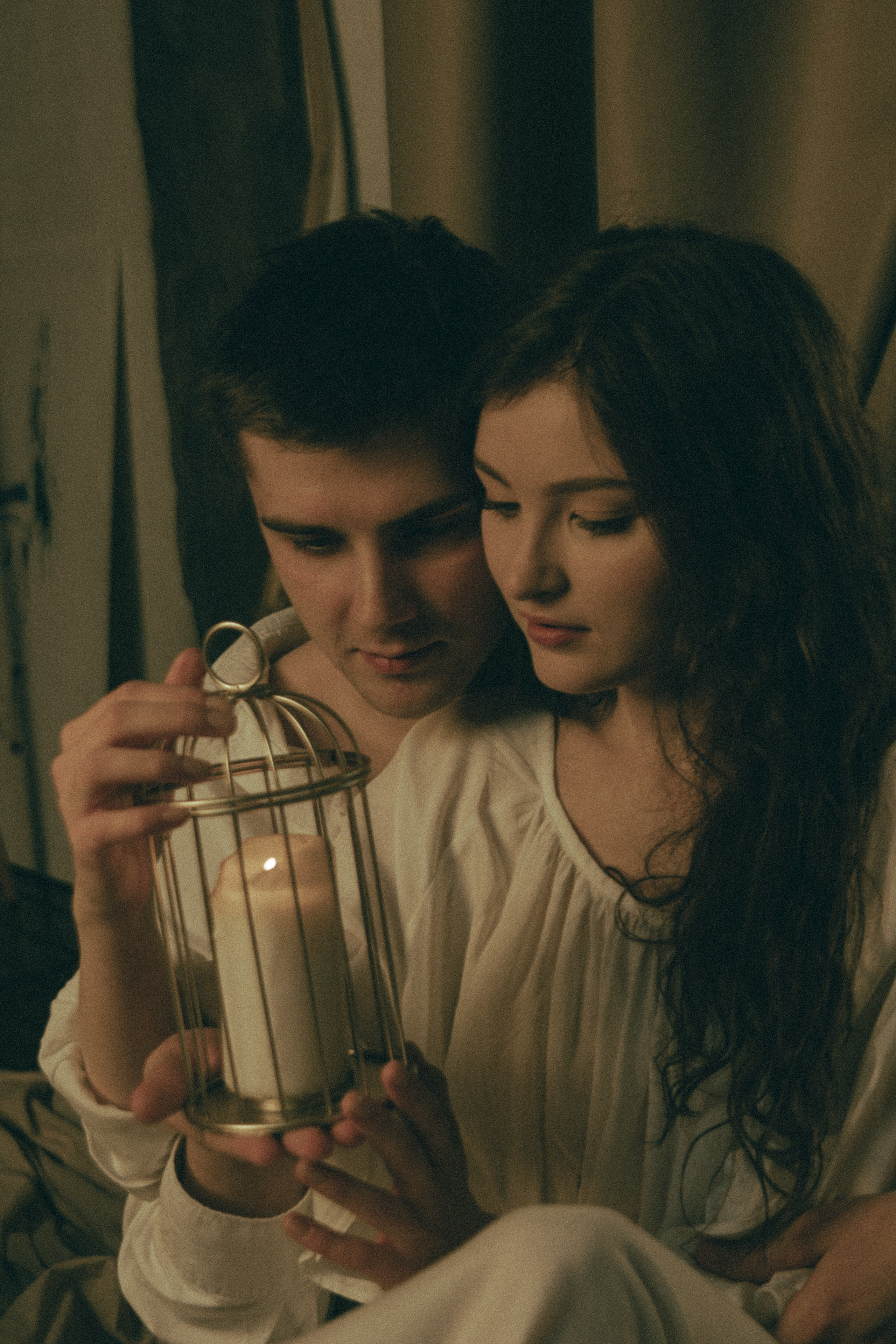 парень и девушка в белой одежде держат в руках подсвечник со свечей