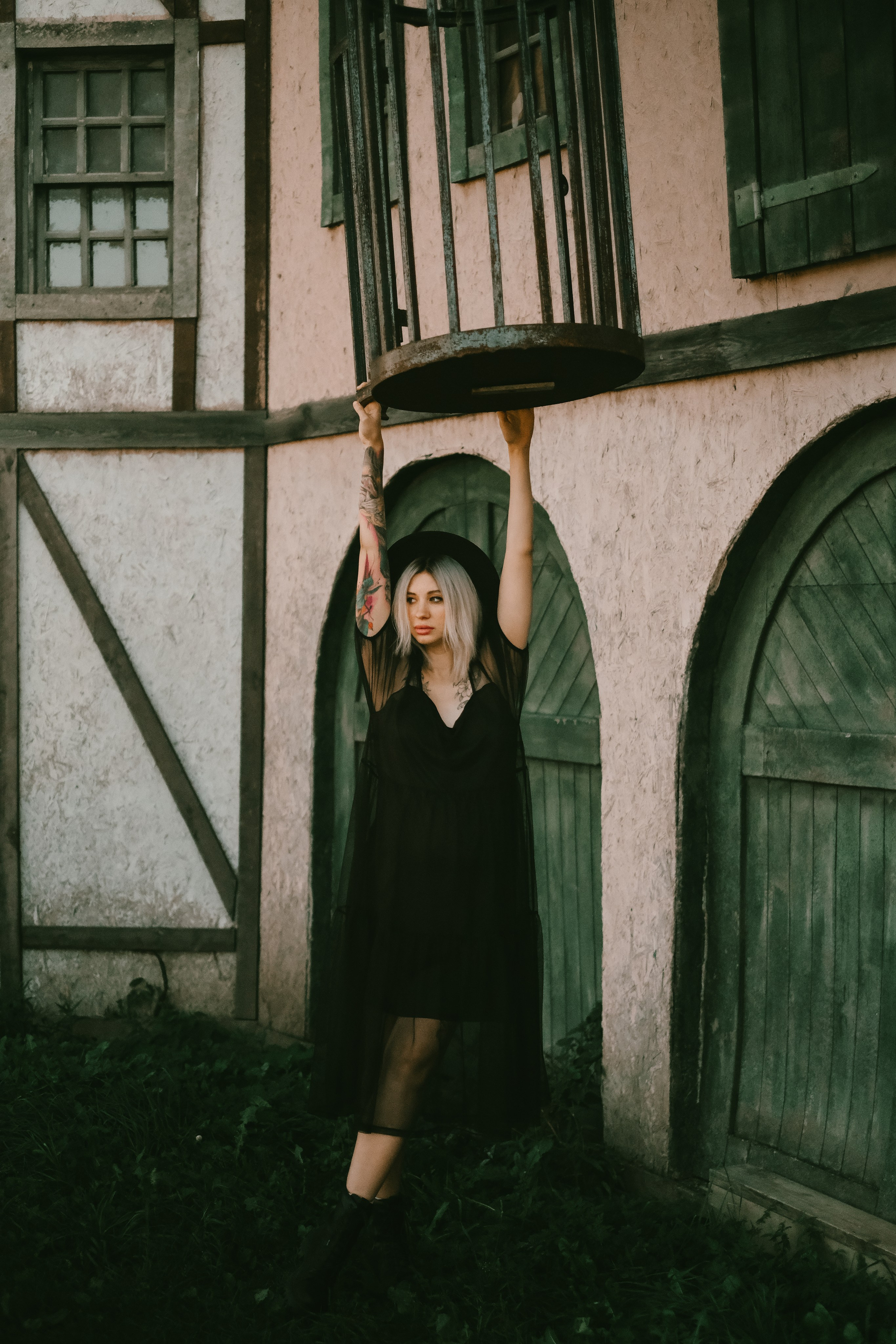 Беременная девушка в черном платье и шляпе в старом городе