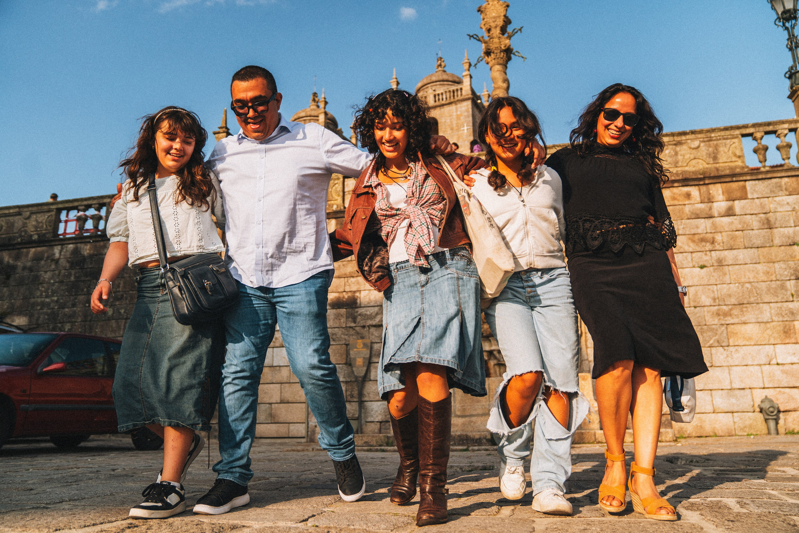 Группа людей гуляет по живописной узкой улочке в Португалии, окружённой старыми домами и зеленью.