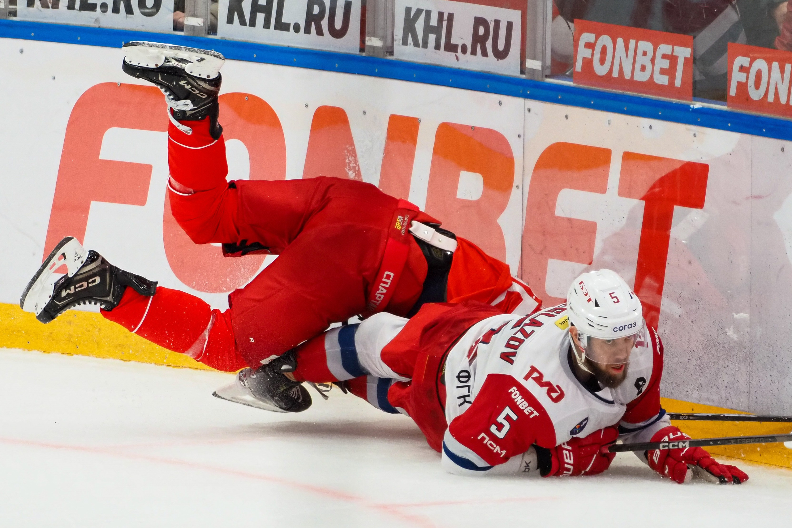 Хоккеисты активно борются за шайбу, падая у борта