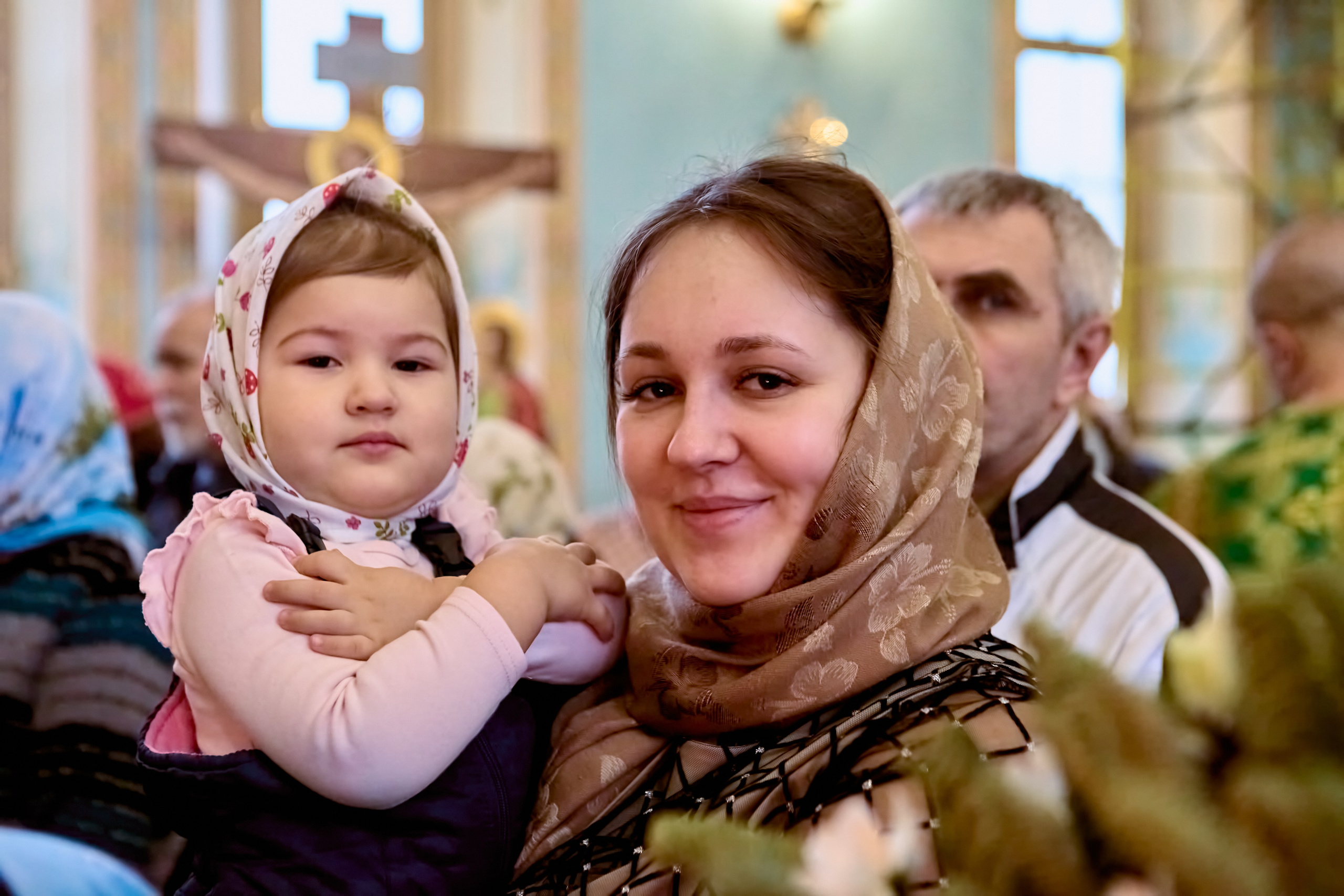 Портрет маленькой девочки на руках у мамы в храме