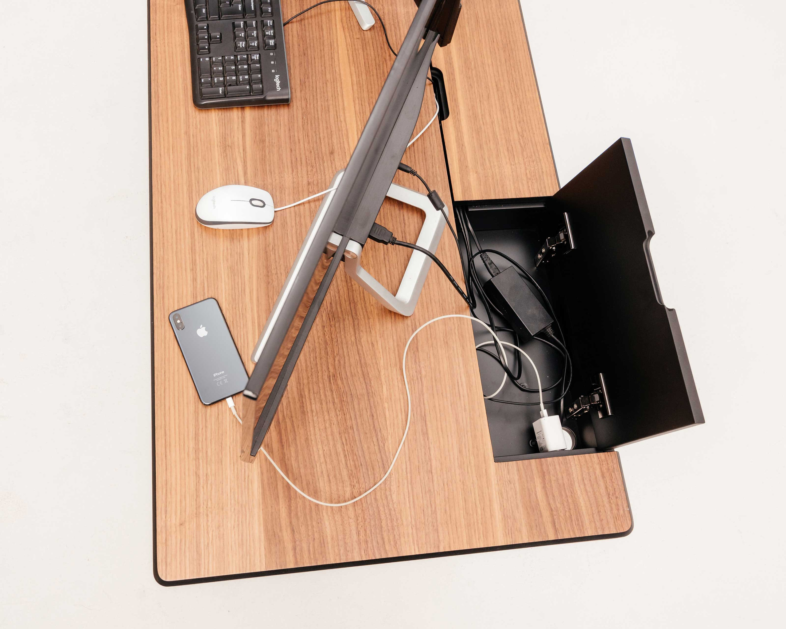 Вид на компьютерный стол сверху, видно, как в открытой крышке, спрятаны провода внутри стола