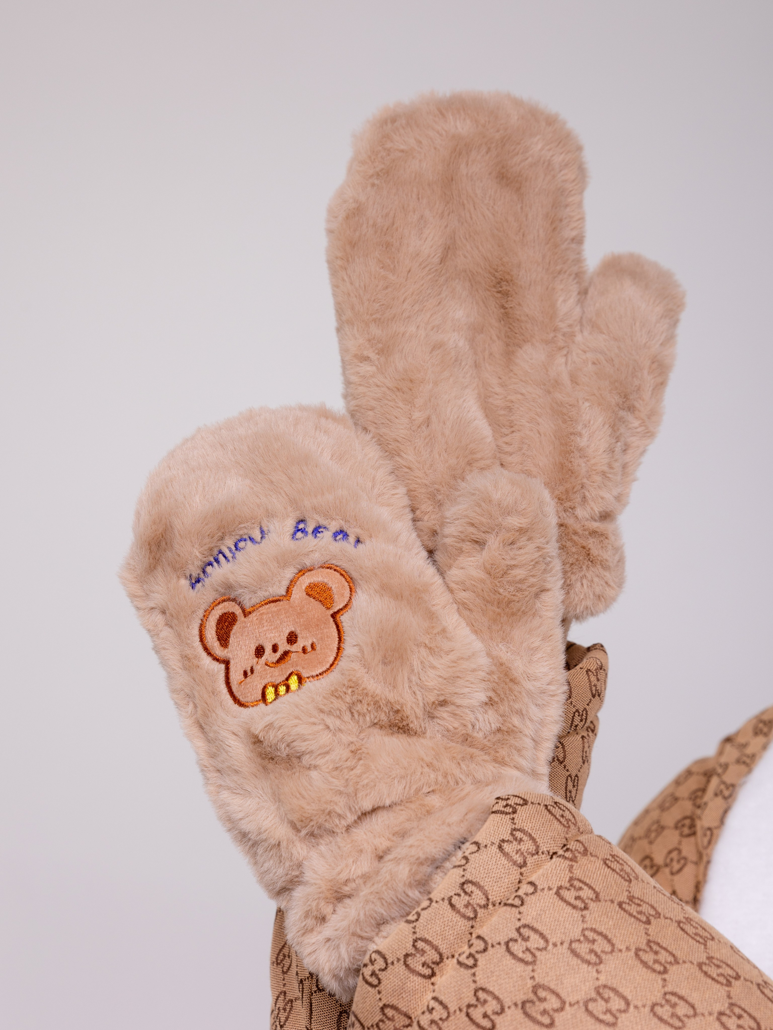На крупном плане пушистые бежевые рукавицы с детскими аппликациями.