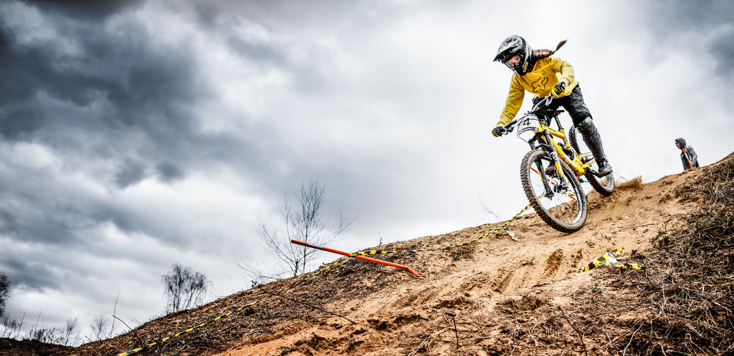 Велосипедист на большой скорости спускается с очень большой горки на соревнованиях