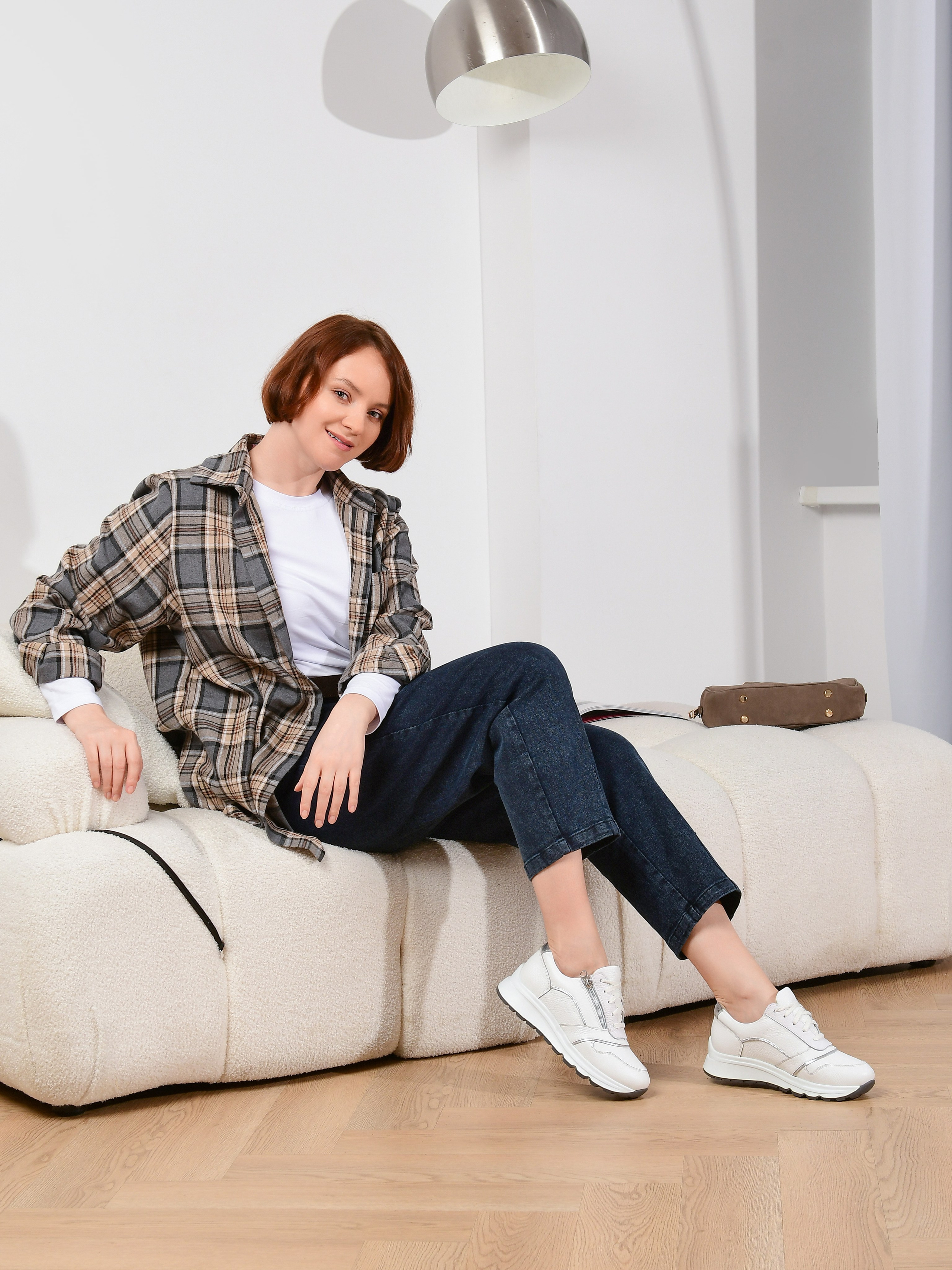 девушка в белых кроссовках сидит на диване