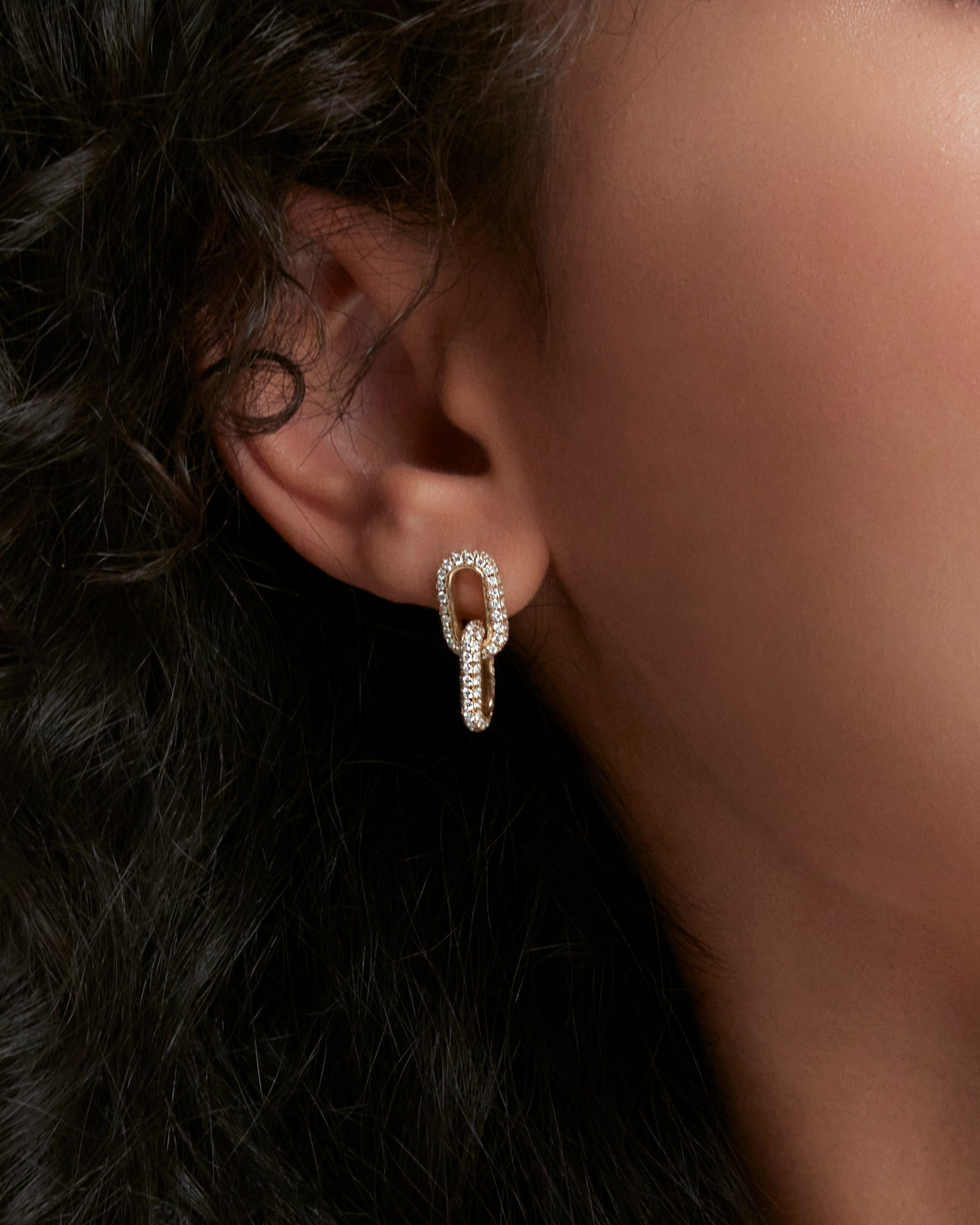 Gold hoop earrings displayed on a model, emphasizing minimalist luxury jewelry design.