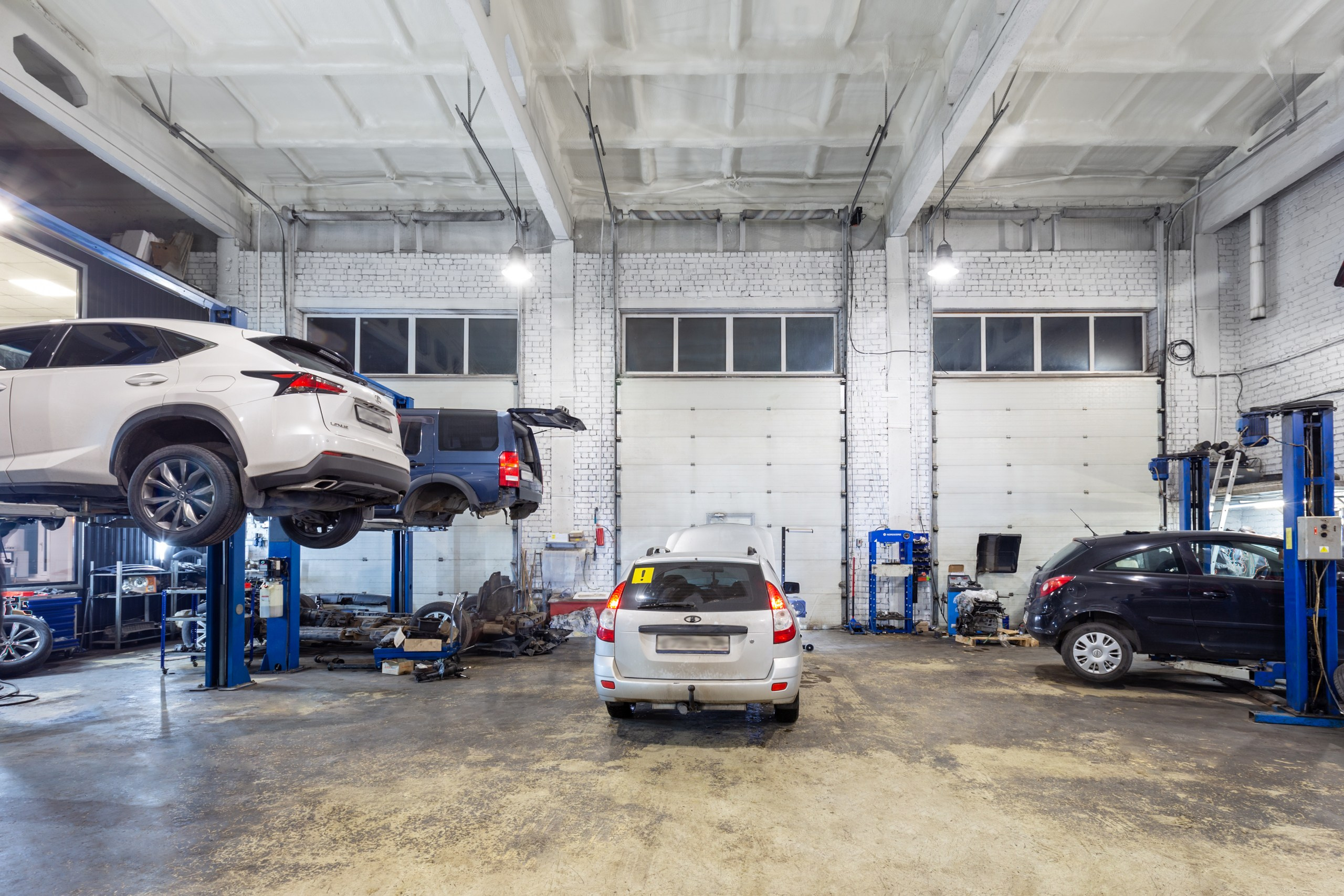 Вид внутри автосервиса. Помещение автомастерской. Внутри авторемонта с белыми стенами.