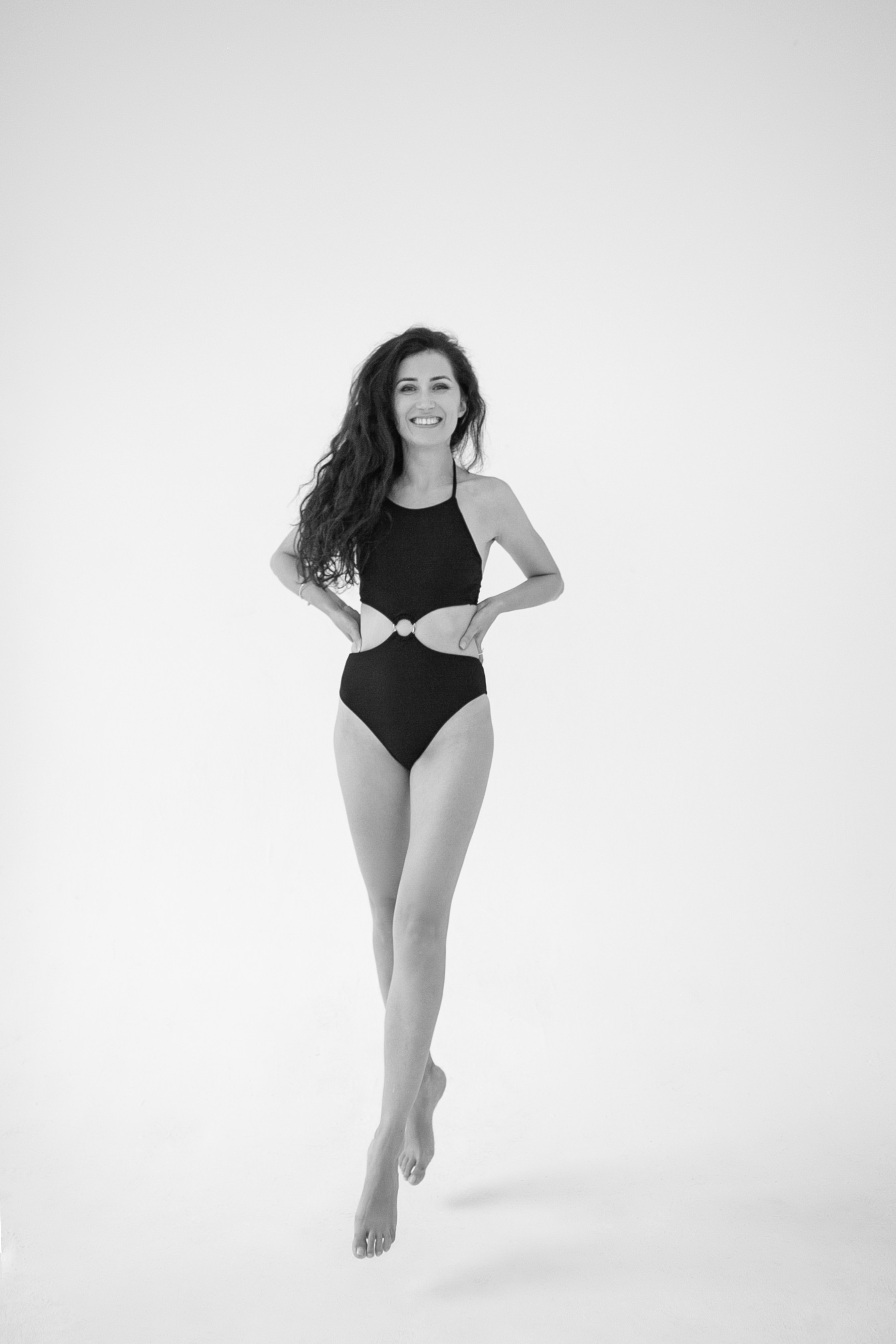 Шикарная женщина с длинными ногами позирует в купальнике на черно-белой фотографии