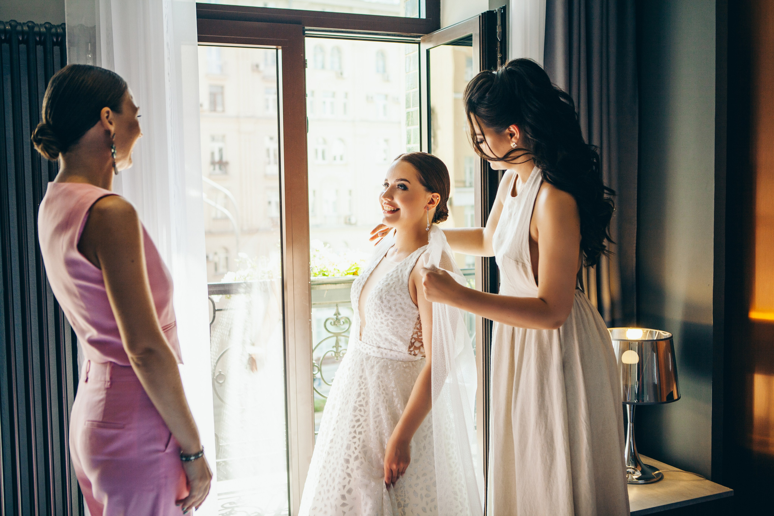 подруги помогают собраться невесте на свадьбу: смеются и поправляют фату
