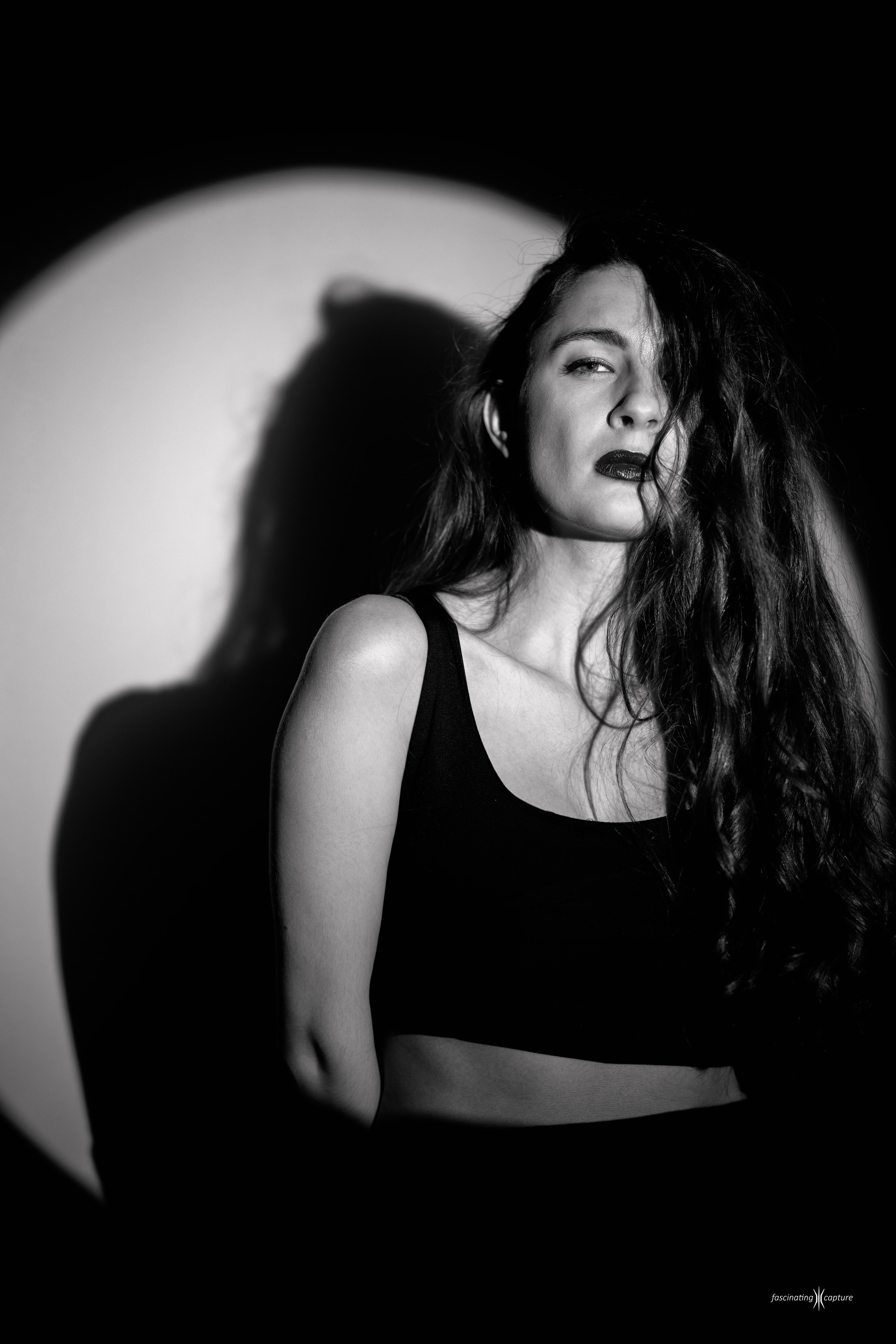 удожественный черно-белый студийный портрет девушки с длинными волосами и красной помадой, драматичное освещение одним источником света с резкими тенями