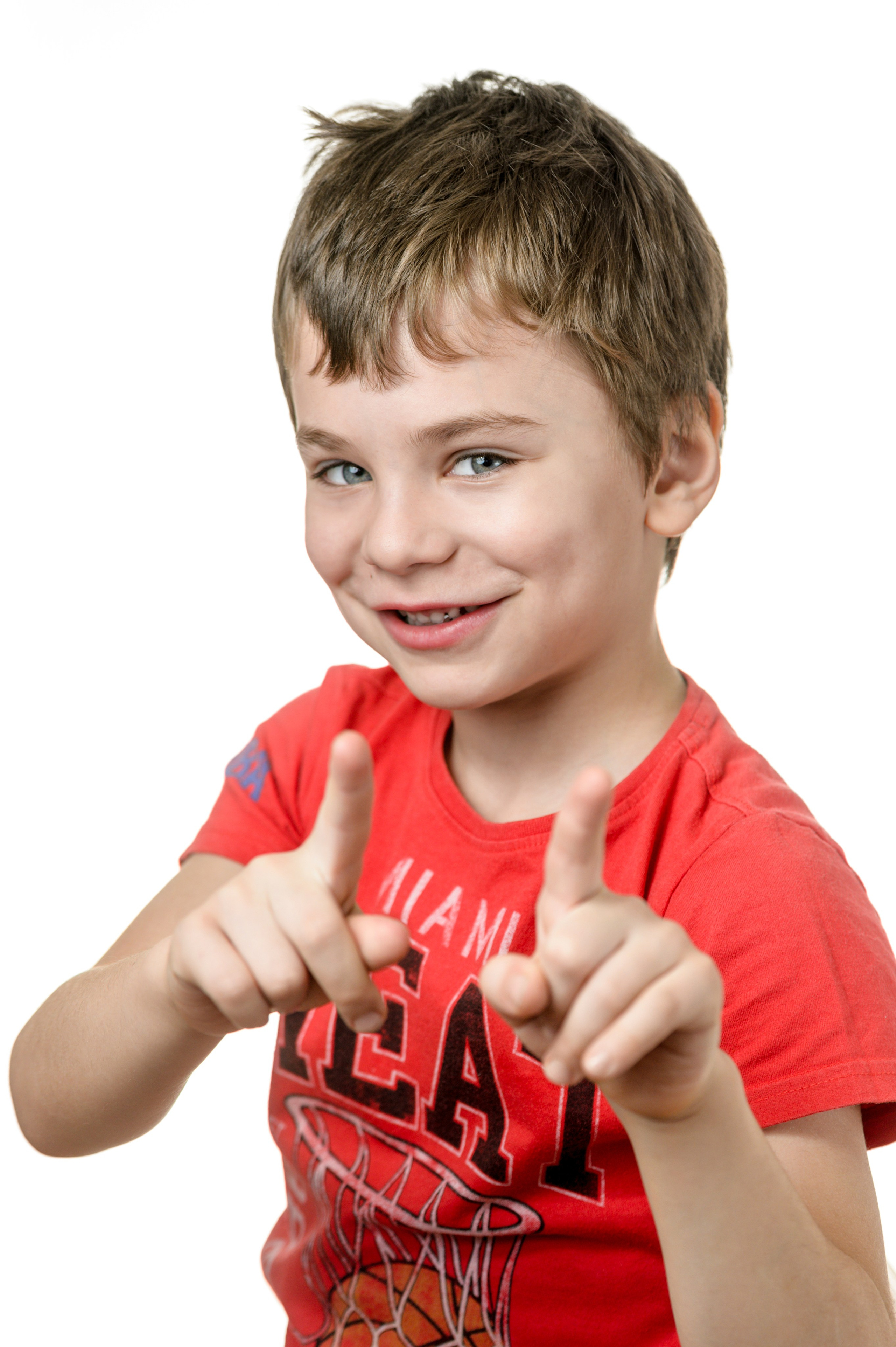 Мальчик в красной футболке показывает жест в студийном портрете на белом фоне.