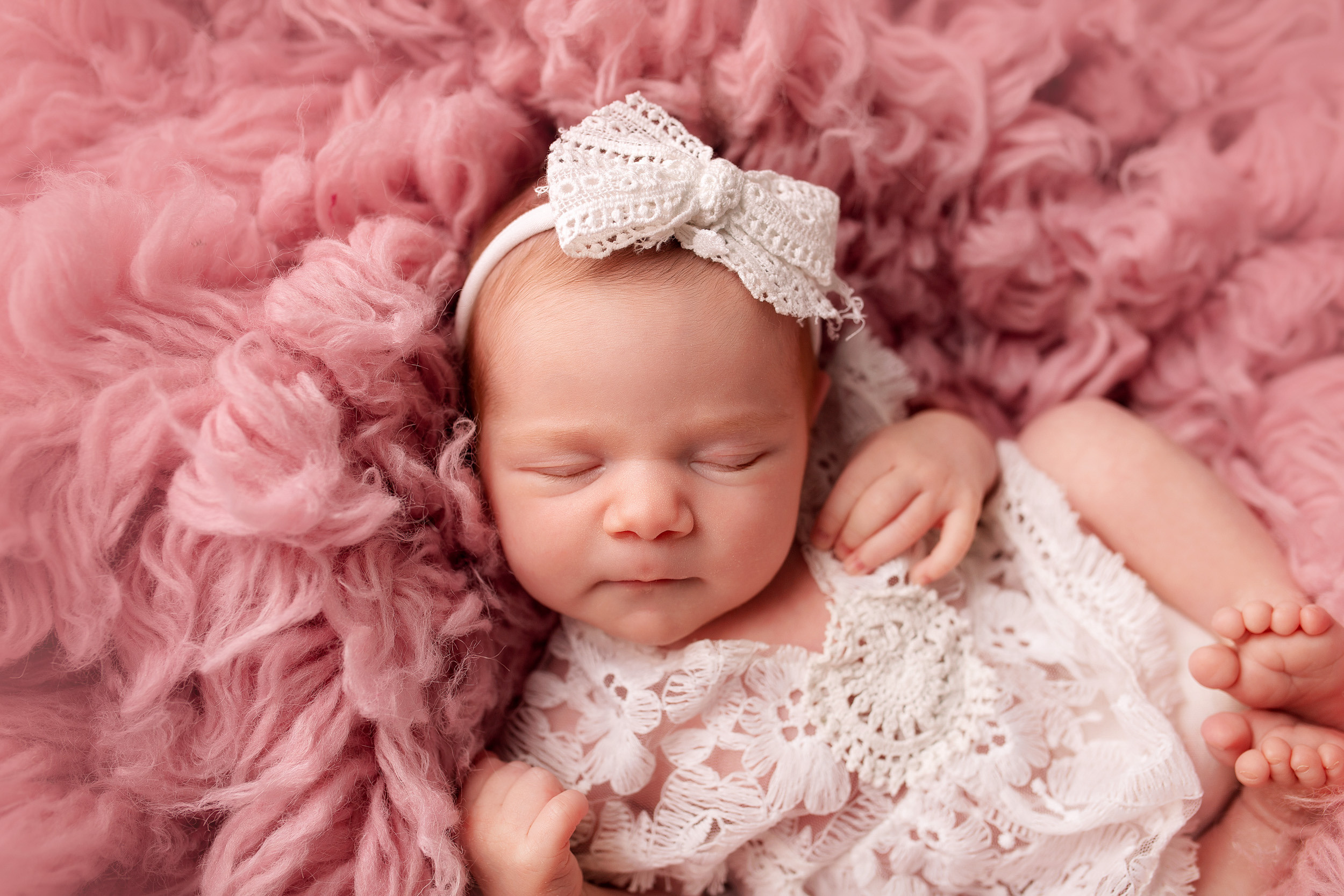 Портрет новорожденной девочки на флокати в позировке на спинке