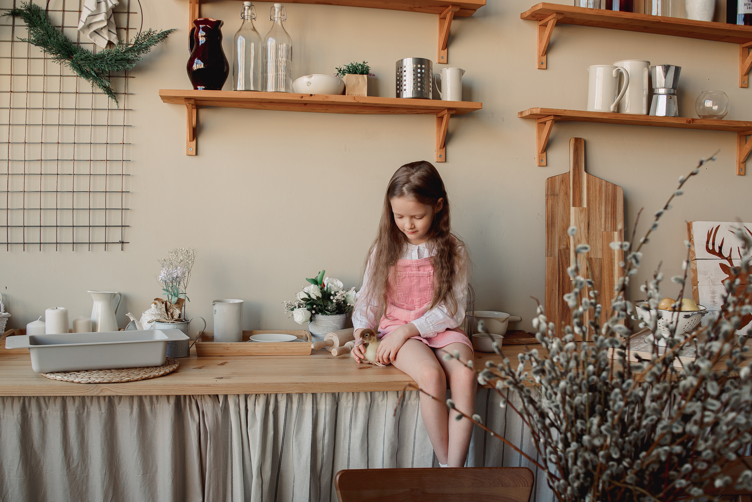 Девочка сидит на столе с утенком