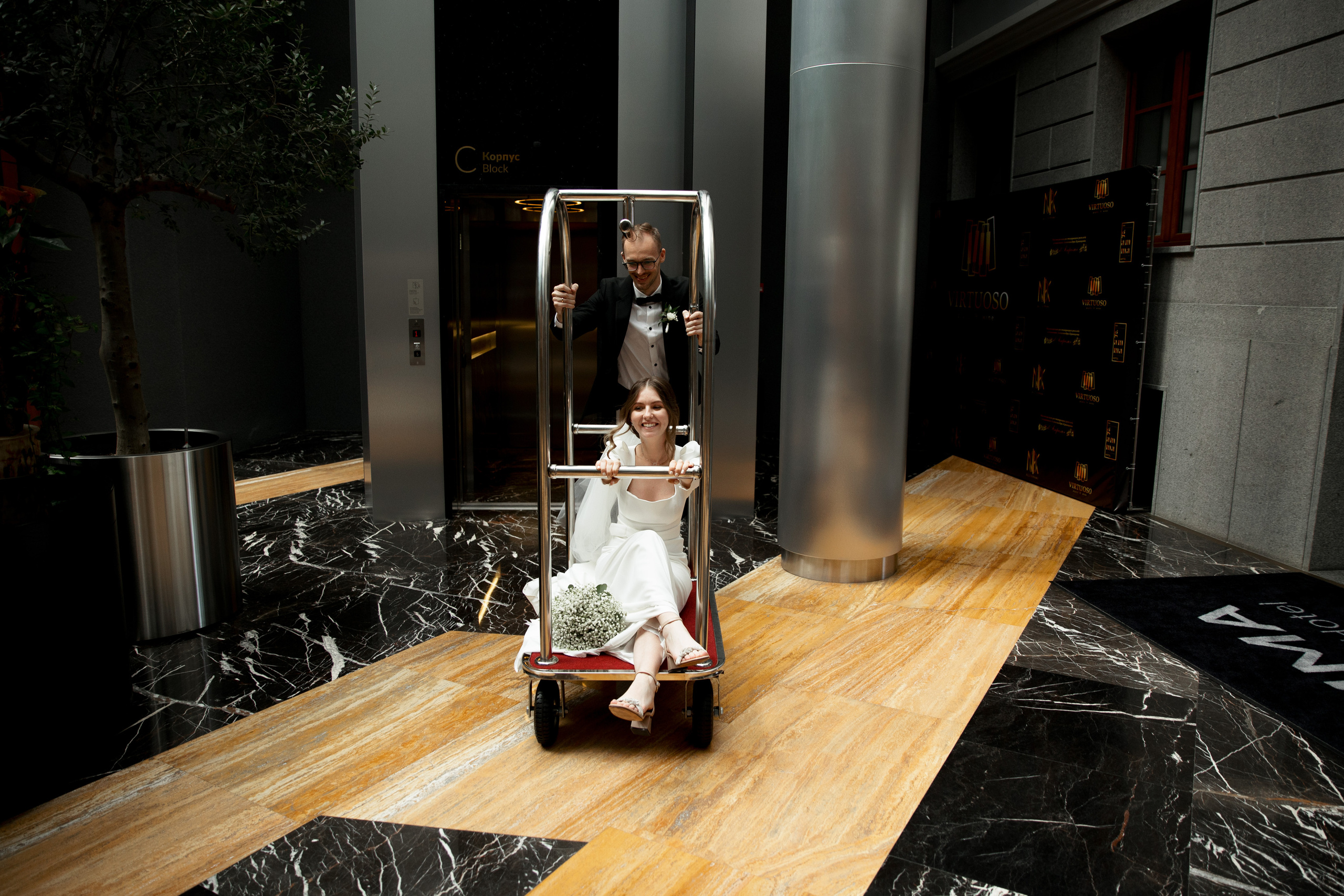 свадебная фотосессия в отеле гамма, жених везет невесту на тележке 