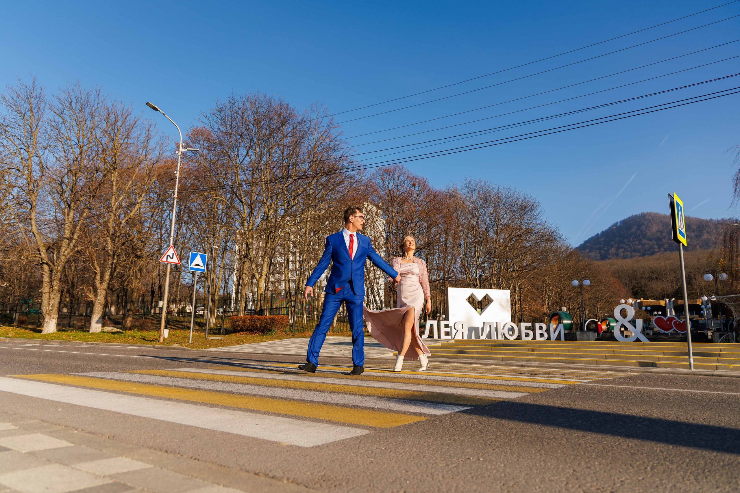 Невеста в свадебном платье улыбается на фоне Аллеи Любви в Железноводске.