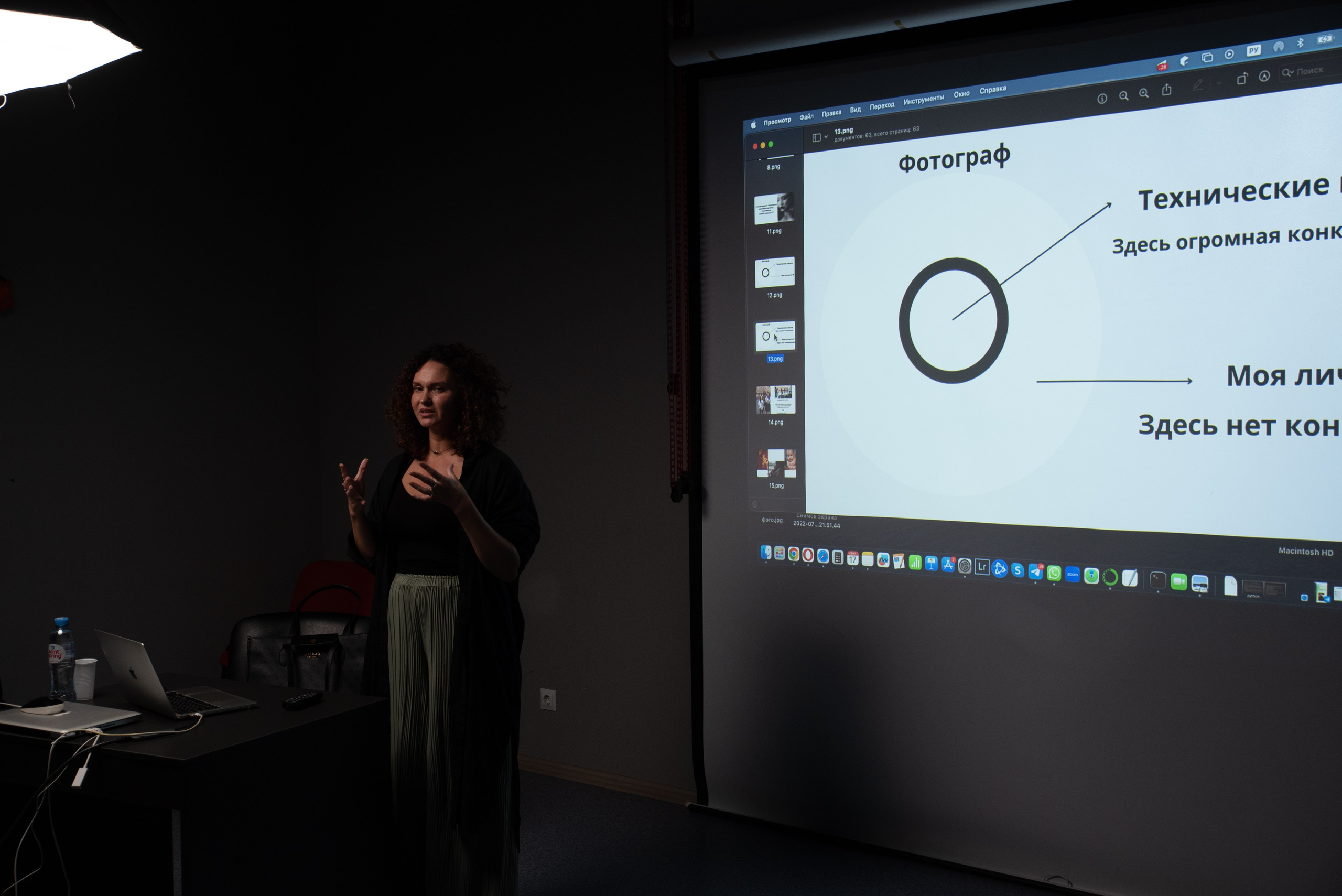 Фотоuраф Надежда Пышкина читает лекцию. На стене за спиной презентация лекции.